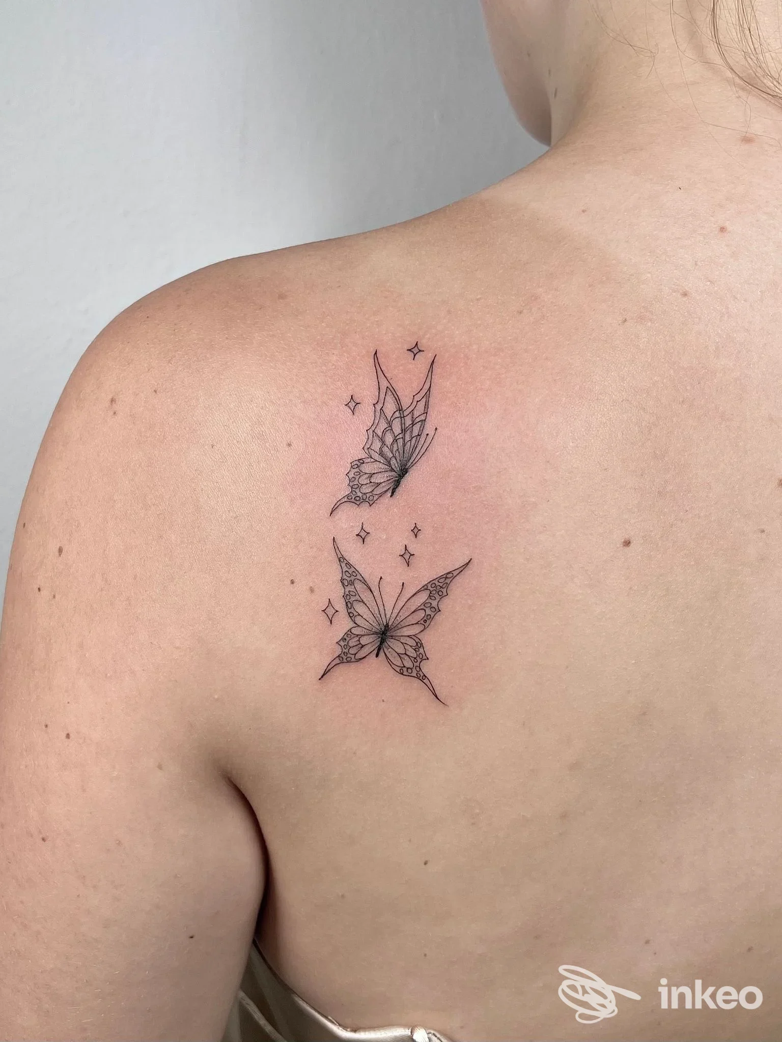 Due piccoli tatuaggi a forma di farfalla a linee sottili sulla scapola, foto fornita da Efi Artist Tattoo&Jewels, Montecatini Terme.