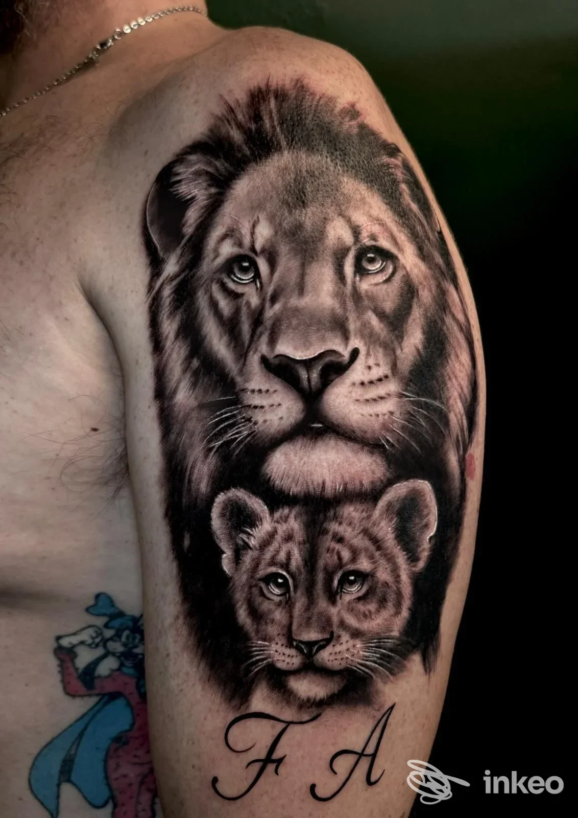 Grande tatuaggio realistico in bianco e nero di un leone e un cucciolo sul braccio superiore, eseguito da Kairos Tattoo Studio a Firenze.