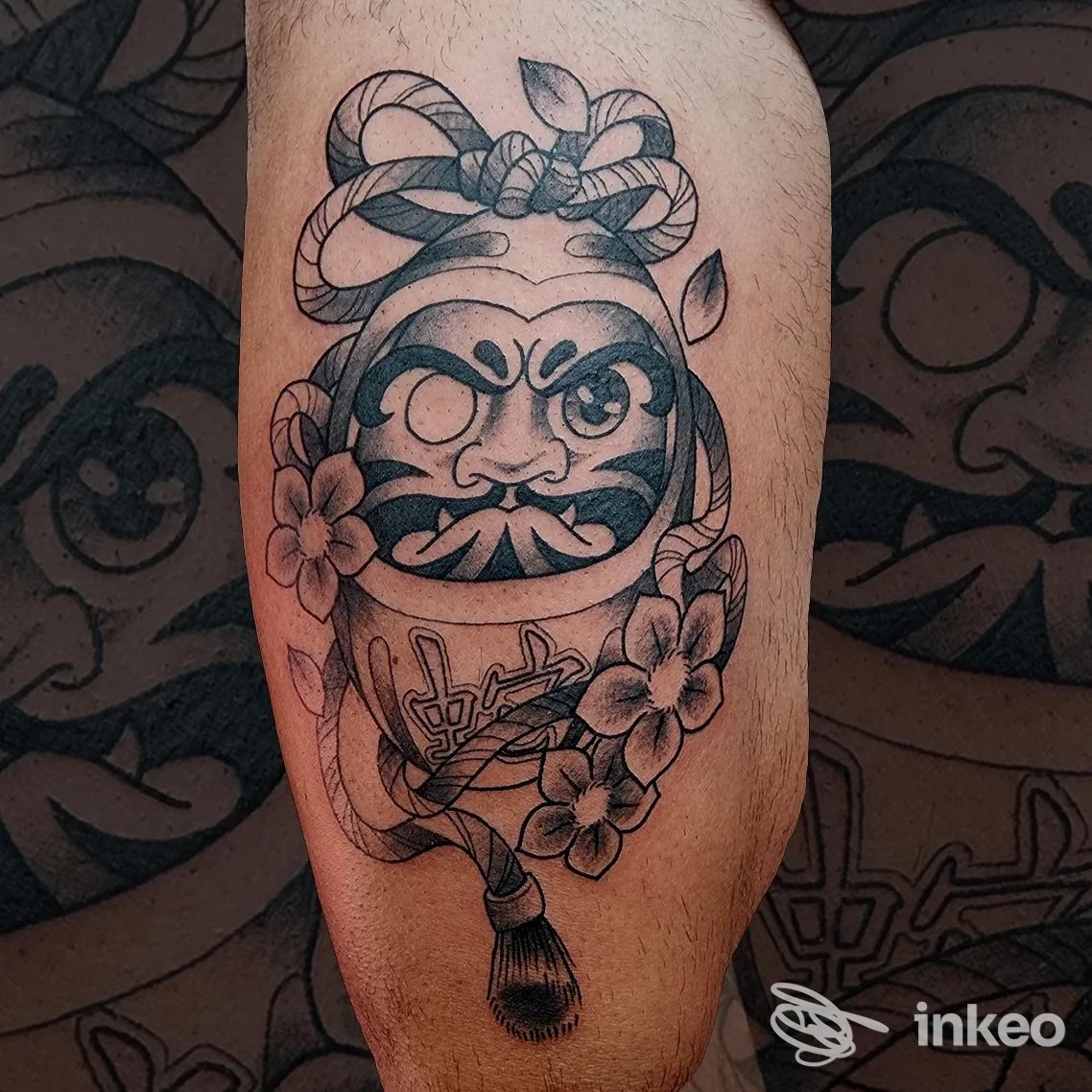 Tatuaggio Daruma in bianco e nero con fiori e corda sul polpaccio, realizzato da Love Hate Tattoo Studio a Marina di Carrara.