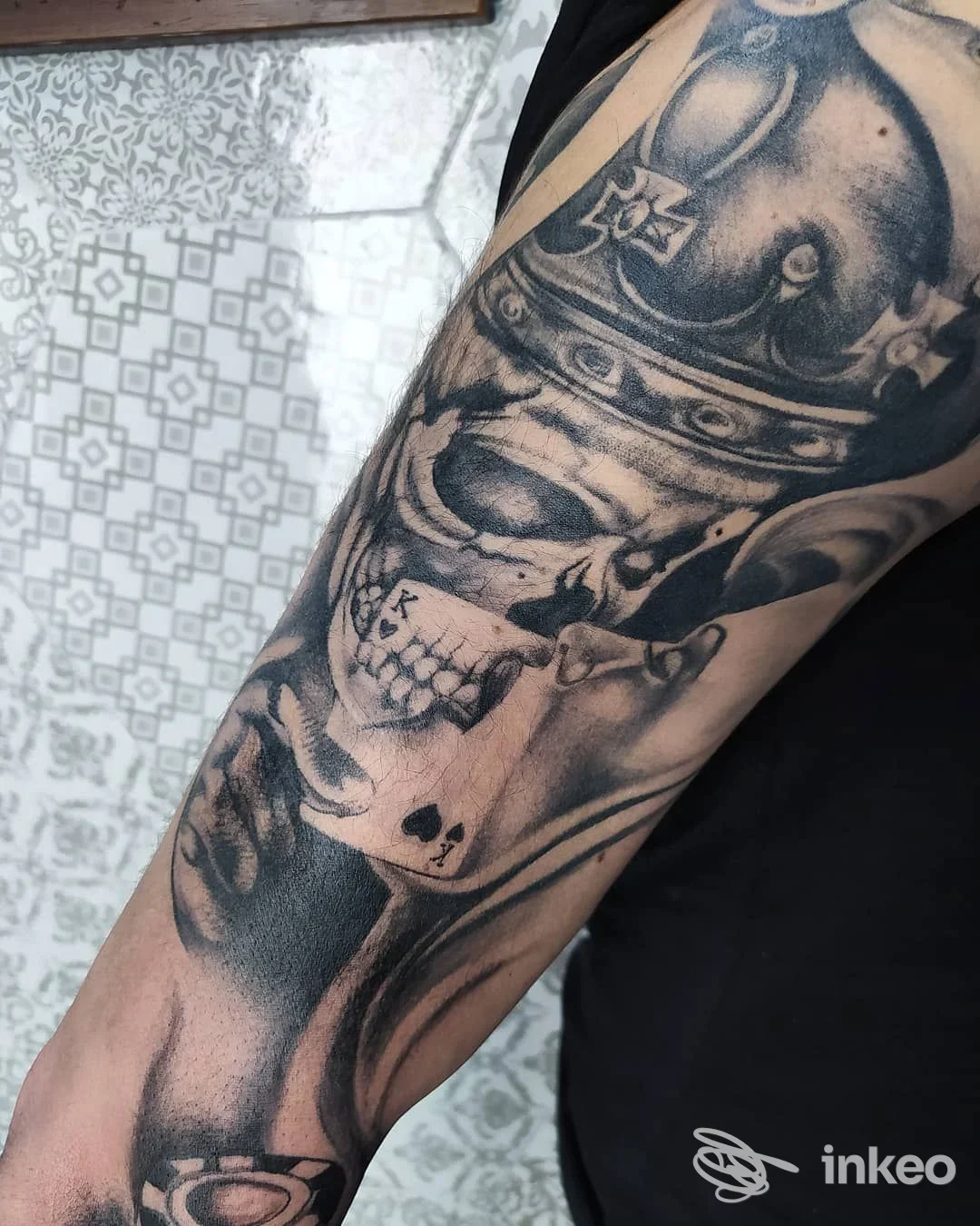 Avambraccio tatuato in stile realistico nero e grigio, dettaglio di teschio e volto — Madame Black Tattoo, Livorno.