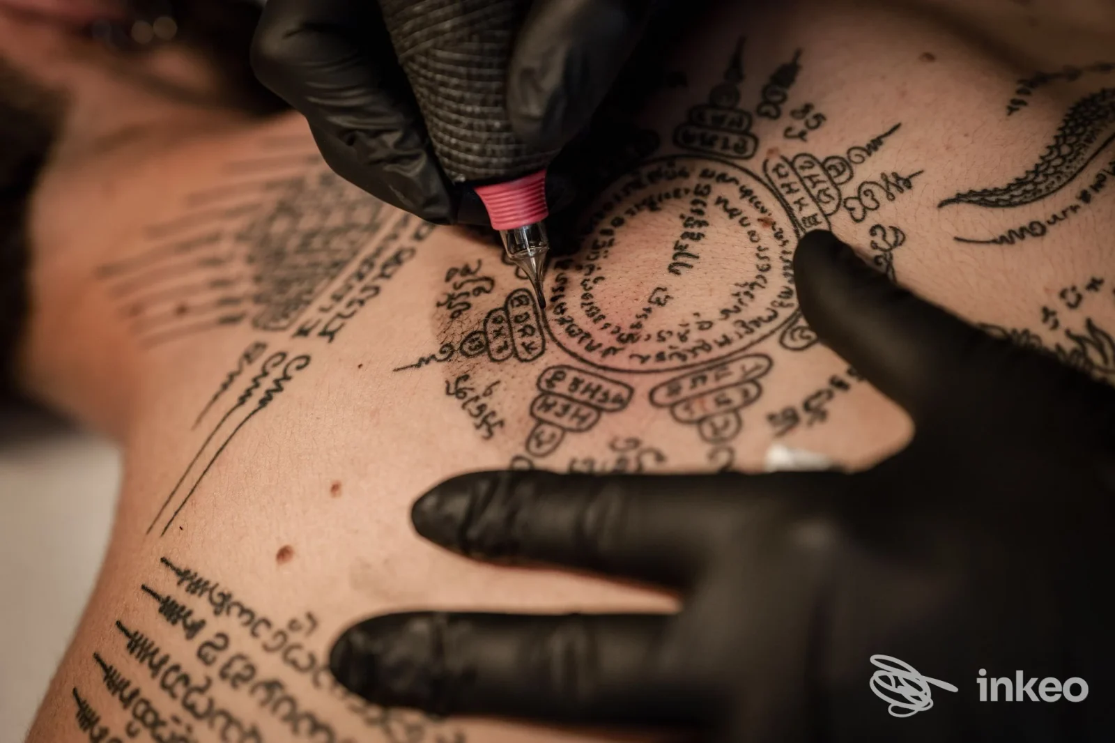 Dettaglio di tatuaggio sul petto in corso con mani guantate e macchinetta, Nexus&Co. Tattoo Studio, Firenze.