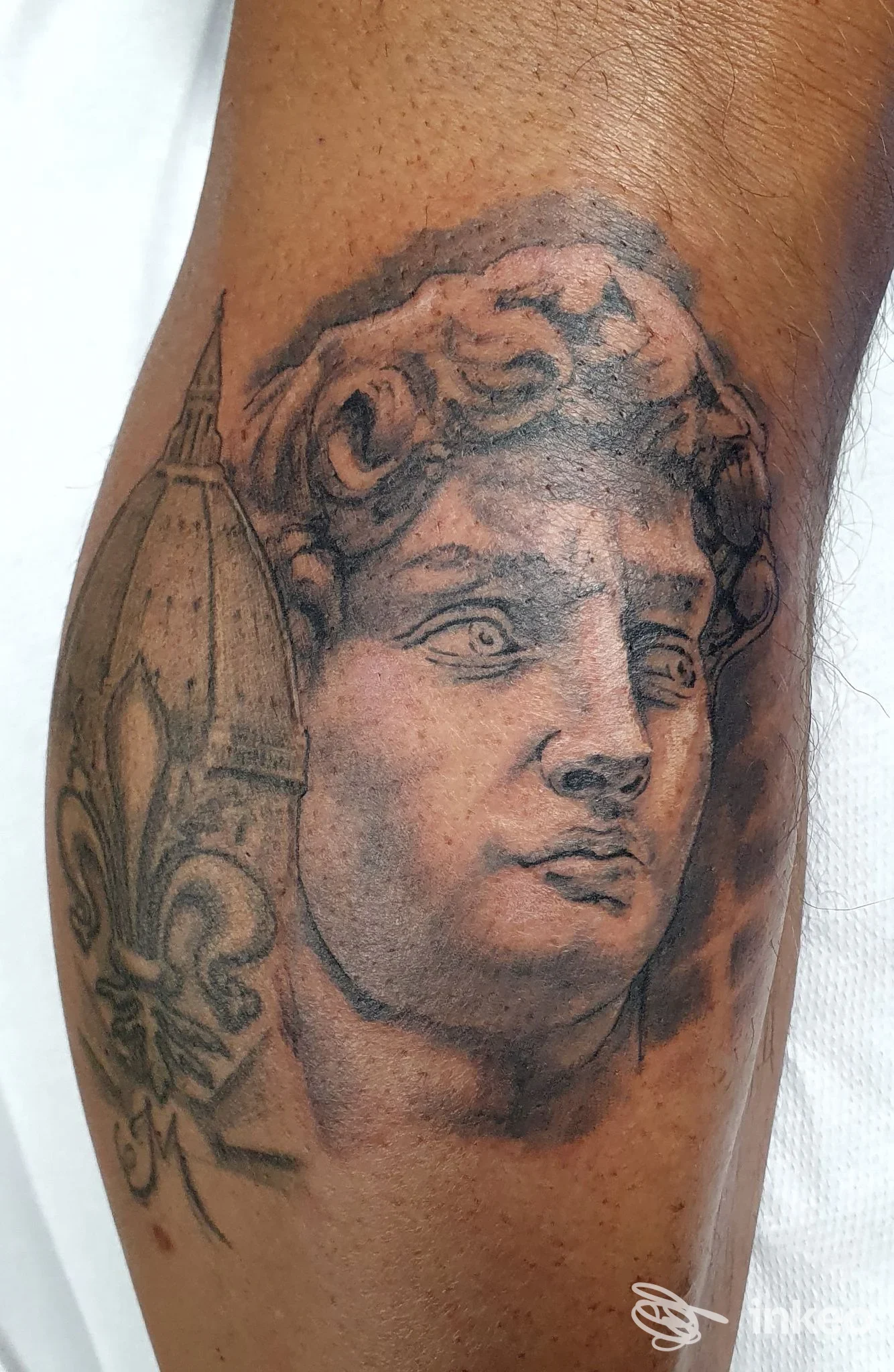 Tatuaggio realistico della testa di un David con giglio su avambraccio, Nexus Tattoo, Montespertoli.