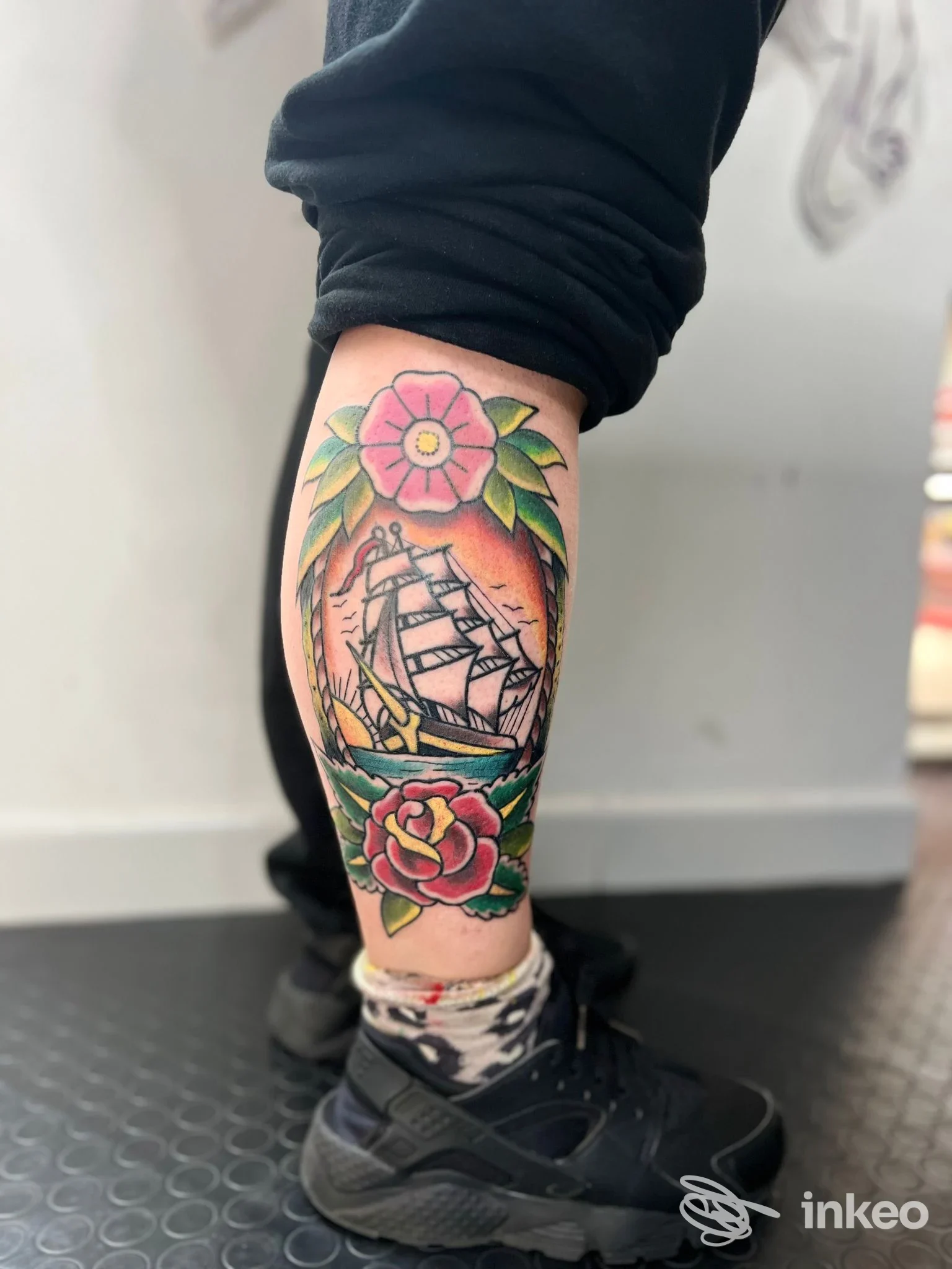 Tatuaggio tradizionale colorato sul polpaccio con veliero, rose e foglie, realizzato da Malasangre tattoo a Livorno.