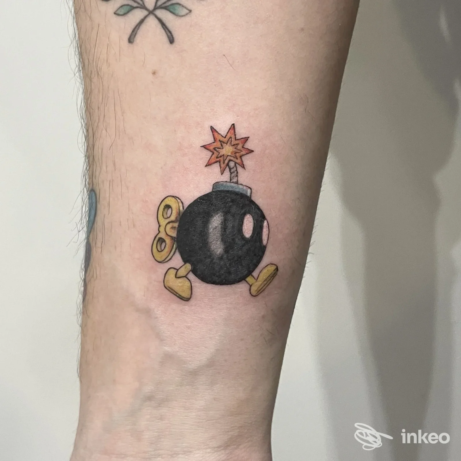 Tattoo su avambraccio raffigurante una bomba nera in stile cartone animato, con fuoco rosso in alto, realizzato da Unconventional Art Shop.