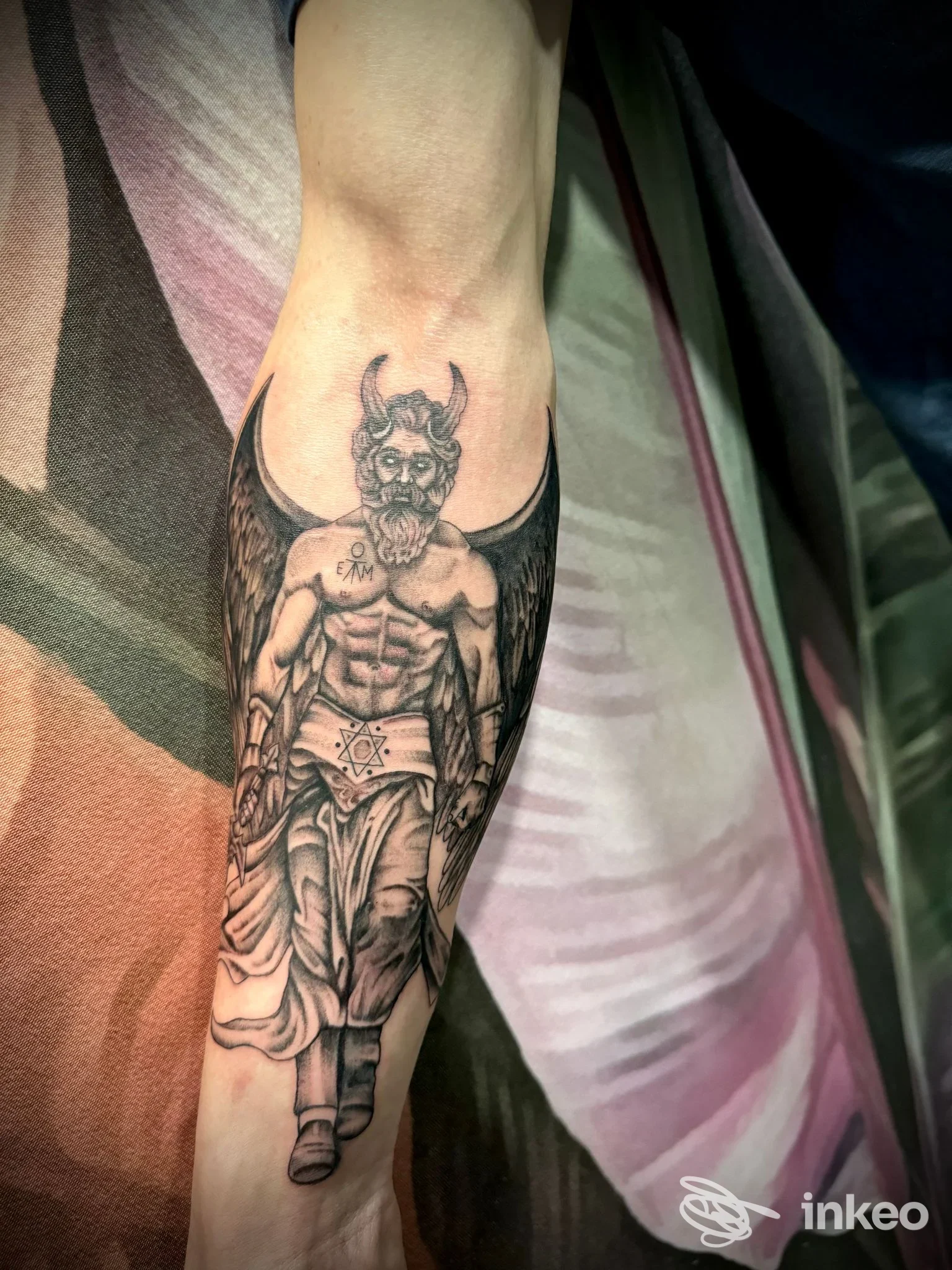 Tatuaggio in bianco e nero su avambraccio raffigurante figura mitologica alata; immagine fornita da Musa tattoo studio, Pietrasanta.