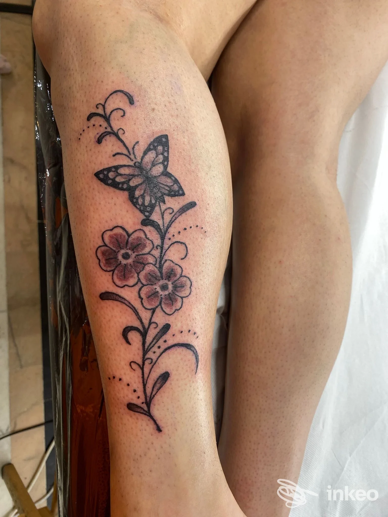 Tatuaggio floreale con farfalla sul polpaccio, foto inviata da Precious Buddha Tattoo Shop Pescia.