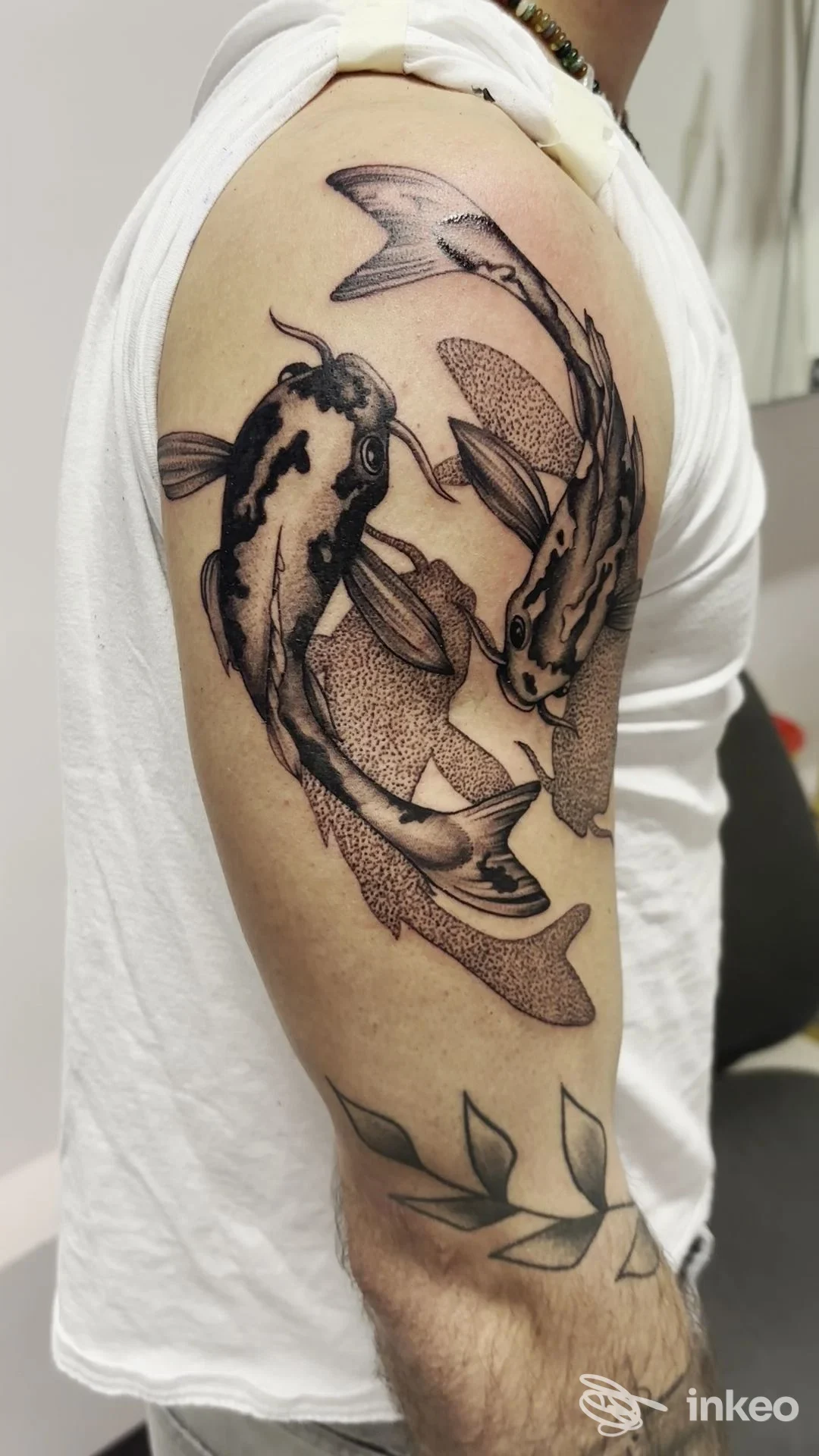 Tatuaggio di due carpe koi in bianco e nero sulla spalla e foglie sull'avambraccio. Tattoo studio anna vannetti, Grassina.