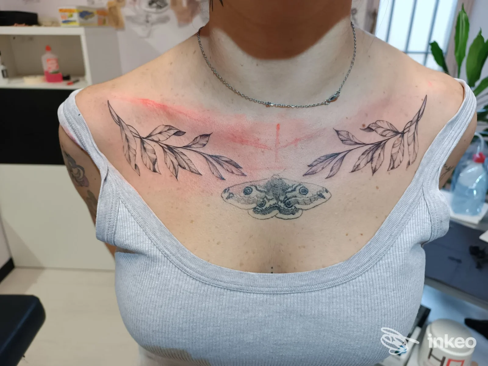 Primo piano del torace con tatuaggi freschi: una falena al centro e due rami sopra le clavicole, Tattoo studio anna vannetti, Grassina.