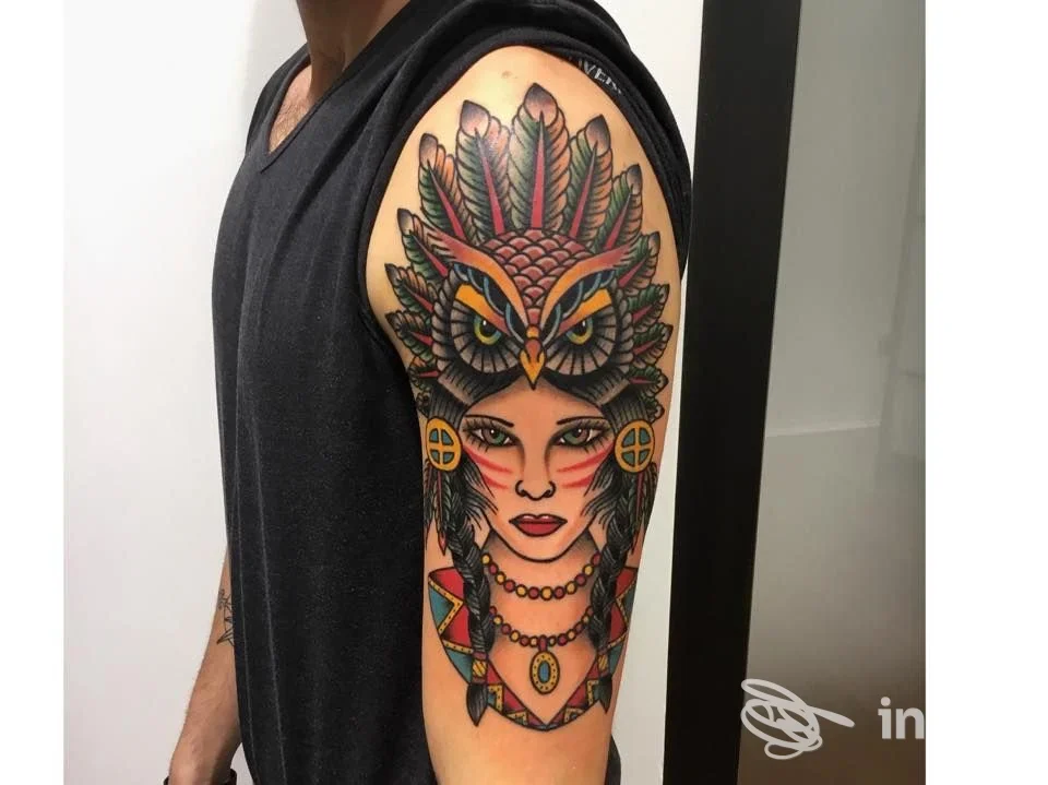 Tatuaggio colorato sul braccio superiore raffigurante donna con copricapo-gufo, realizzato da Teschio Nero Tattoo Shop, Pistoia.