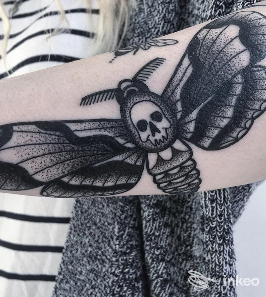 Tatuaggio nero su avambraccio raffigurante una creatura alata con teschio, fotografia inviata dallo studio Trick Tattoo a San Miniato.