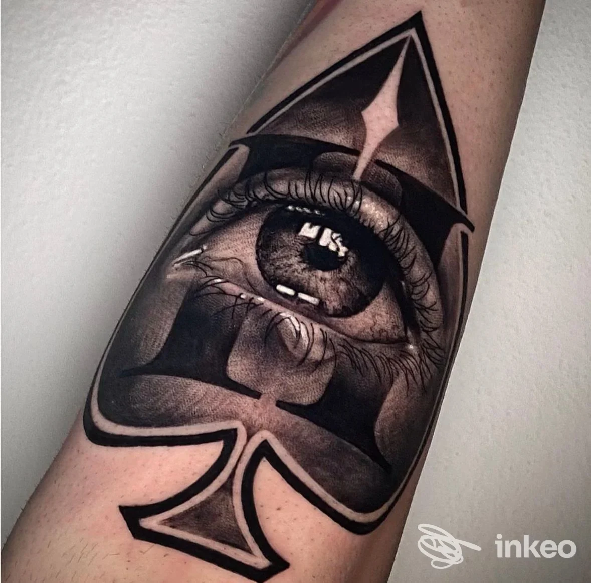 Tatuaggio realistico in bianco e nero su avambraccio: una carta a picche con un occhio dettagliato. Trick Tattoo, San Miniato.