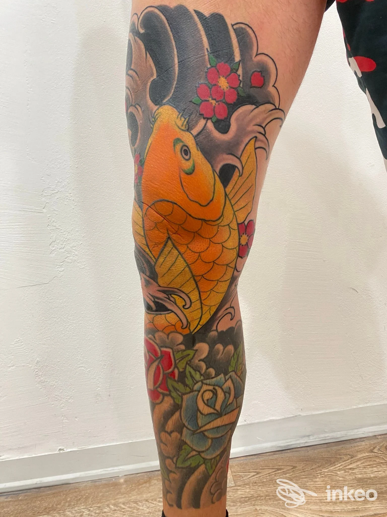 Grande tatuaggio su polpaccio con un koi giallo e fiori colorati, lavoro eseguito da True love tattoo & Piercing a Viareggio.