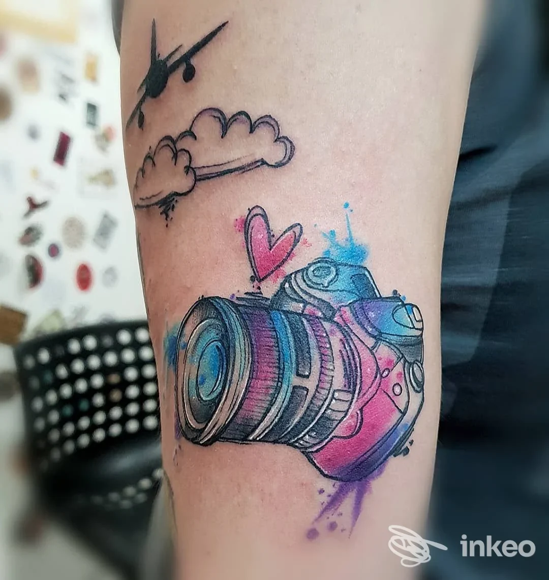 Tatuaggio acquerello di una fotocamera sull'avambraccio, opera eseguita da Velvet Tattoo a Cecina.