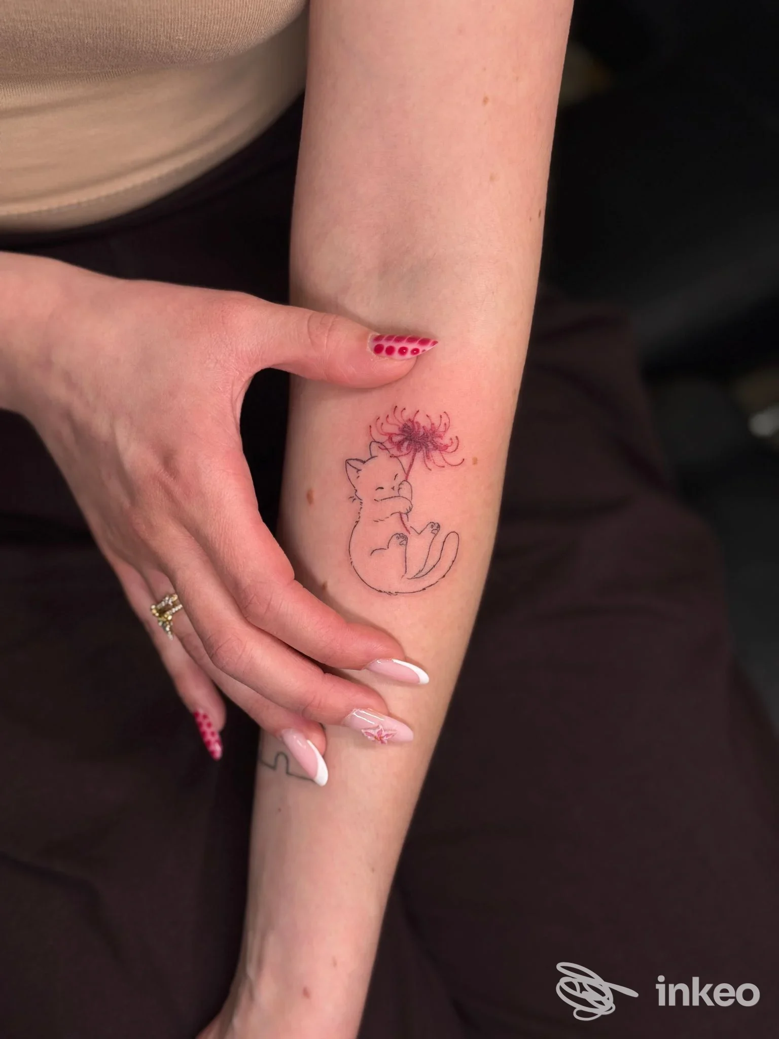 Tatuaggio di un piccolo gatto con fiore sull'avambraccio, foto inviata da 31 ink Tattoo, Rovereto.