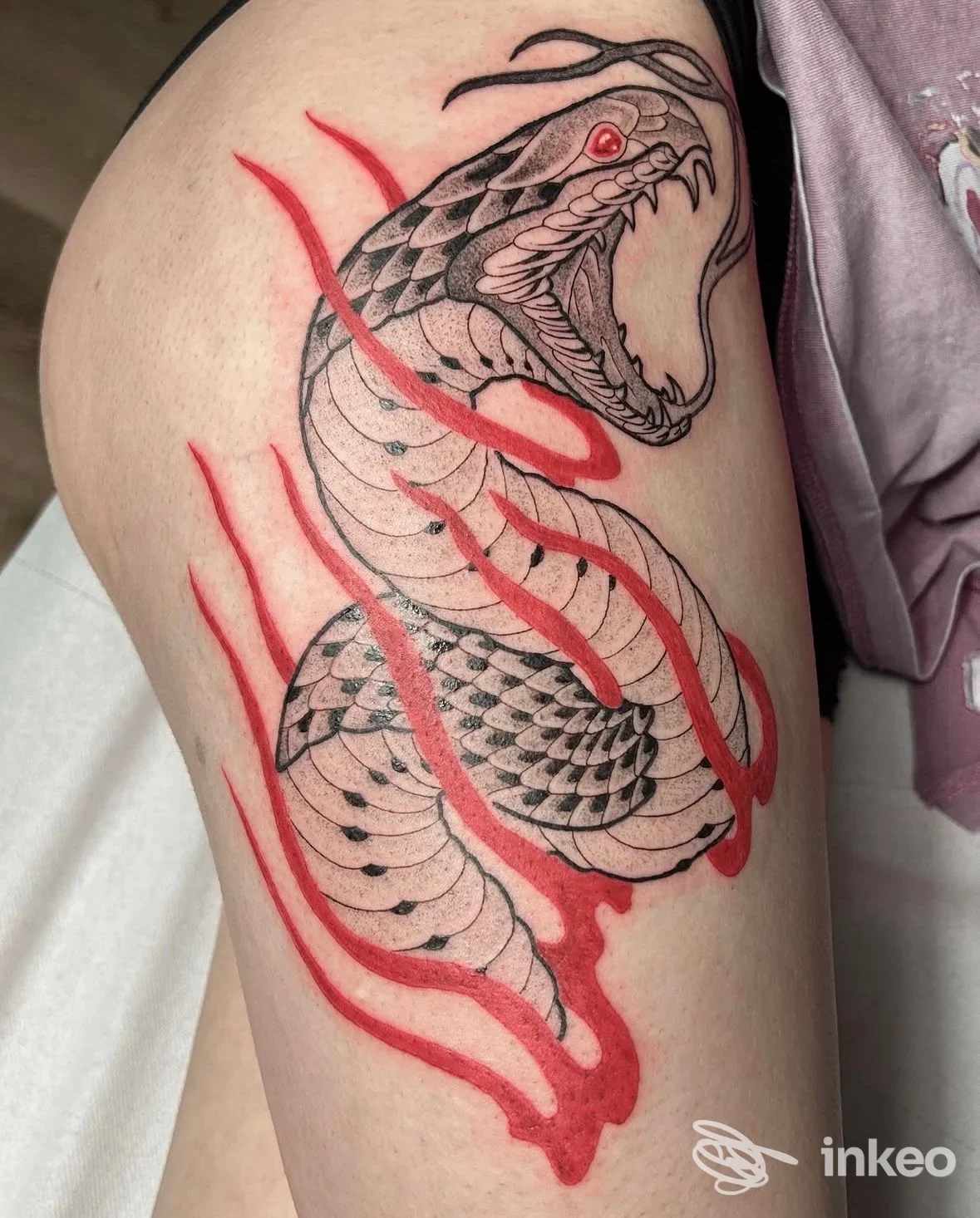 Tatuaggio di un serpente nero con accenti rossi sulla coscia, foto fornita da Anthracite Tattoo Studio, Trento.