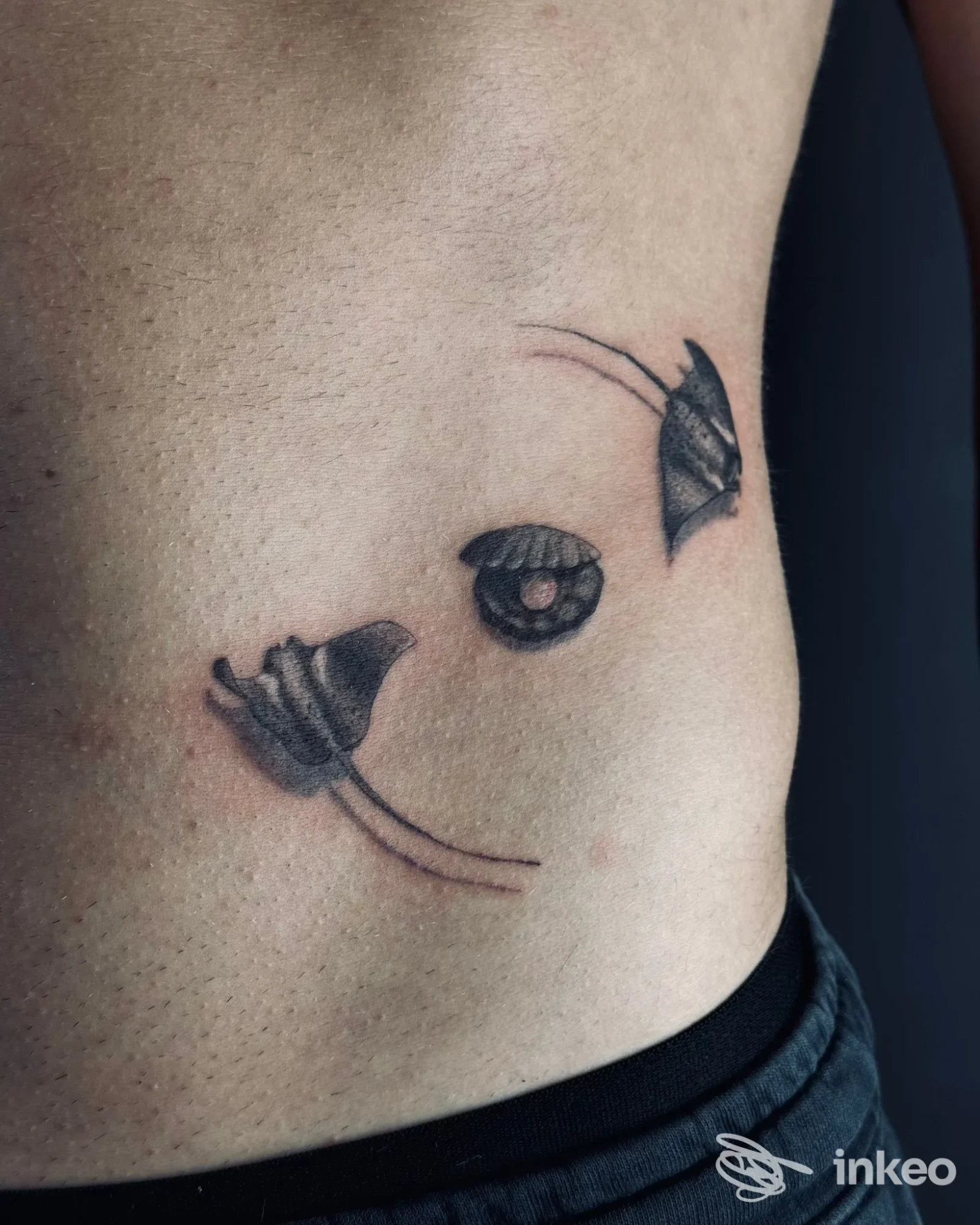 Tatuaggio nero minimal sul fianco, foto fornita da Anthracite Tattoo Studio, Trento.