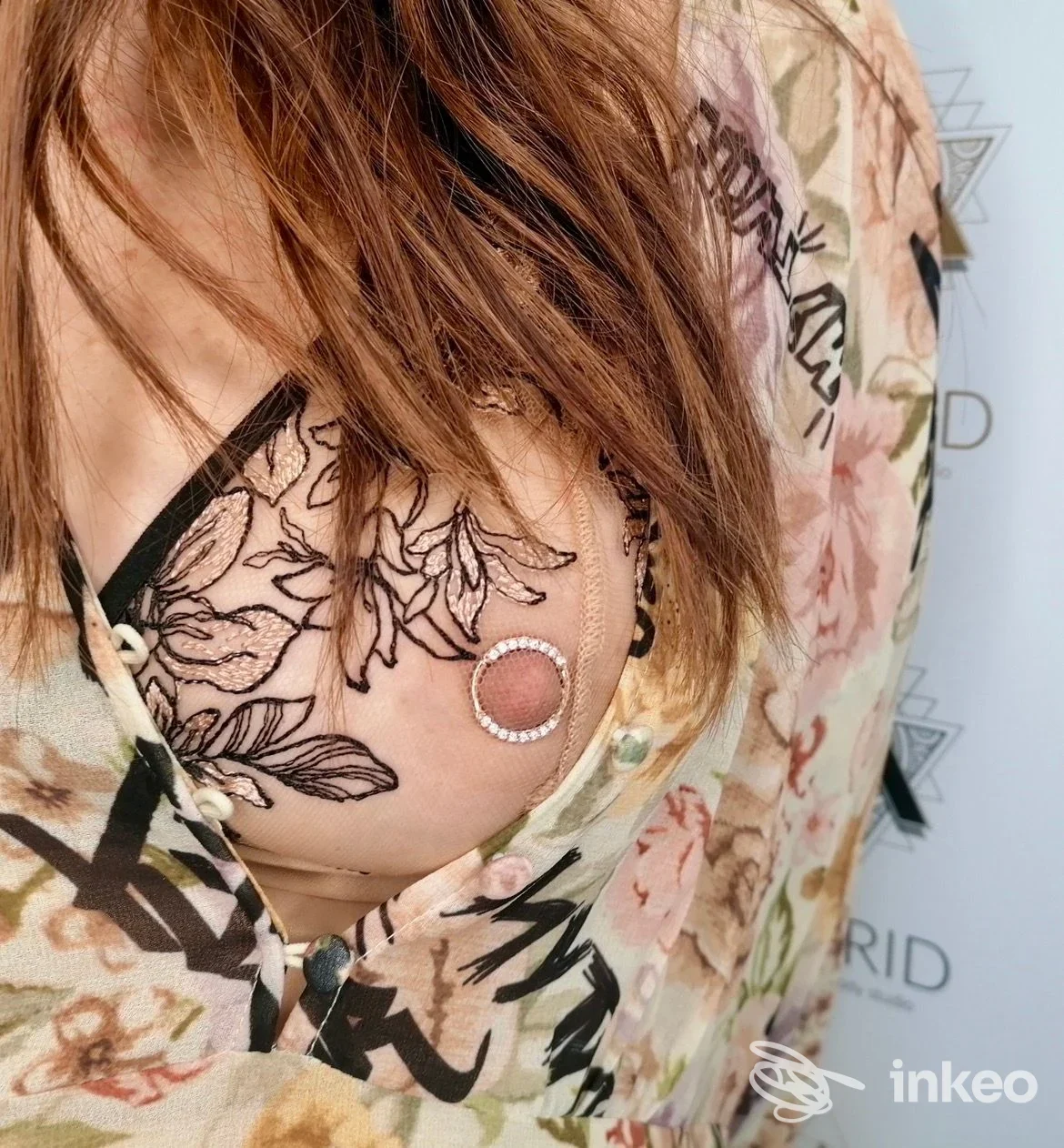 Primo piano del seno con piercing al capezzolo e tatuaggio floreale, foto scattata presso Astrid Body Piercing Studio a Bolzano.