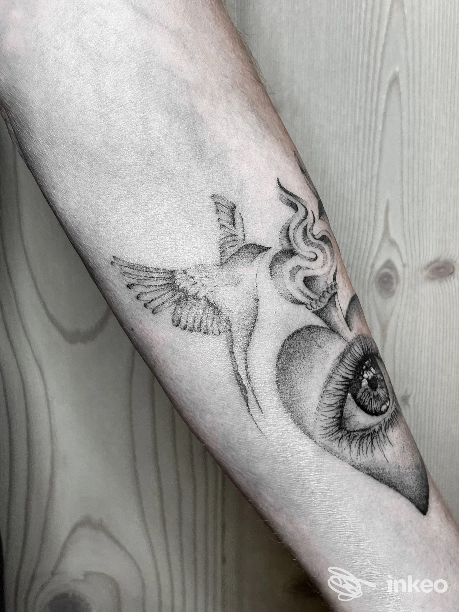 Tatuaggio in bianco e nero su avambraccio con colibrì e occhio, Athena Tattoo Studio, Cles.