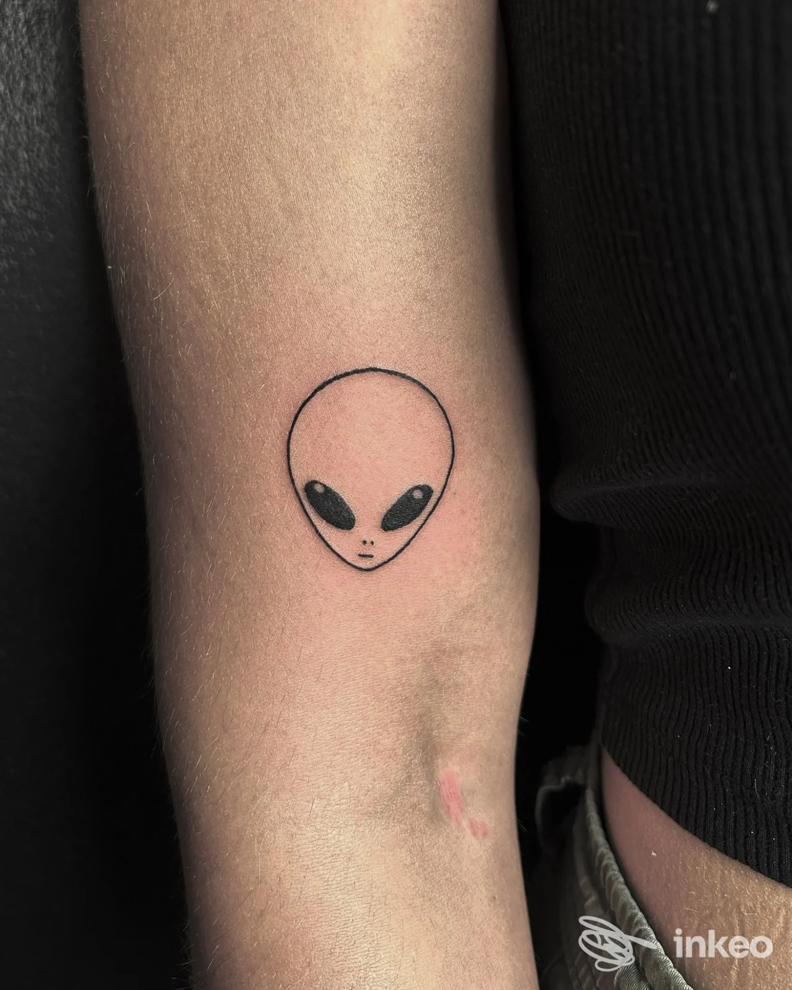 Piccolo tatuaggio minimal di una testa di alieno sull'avambraccio interno, foto pubblicata da Bootleg Art Tattoo, Riva del Garda.