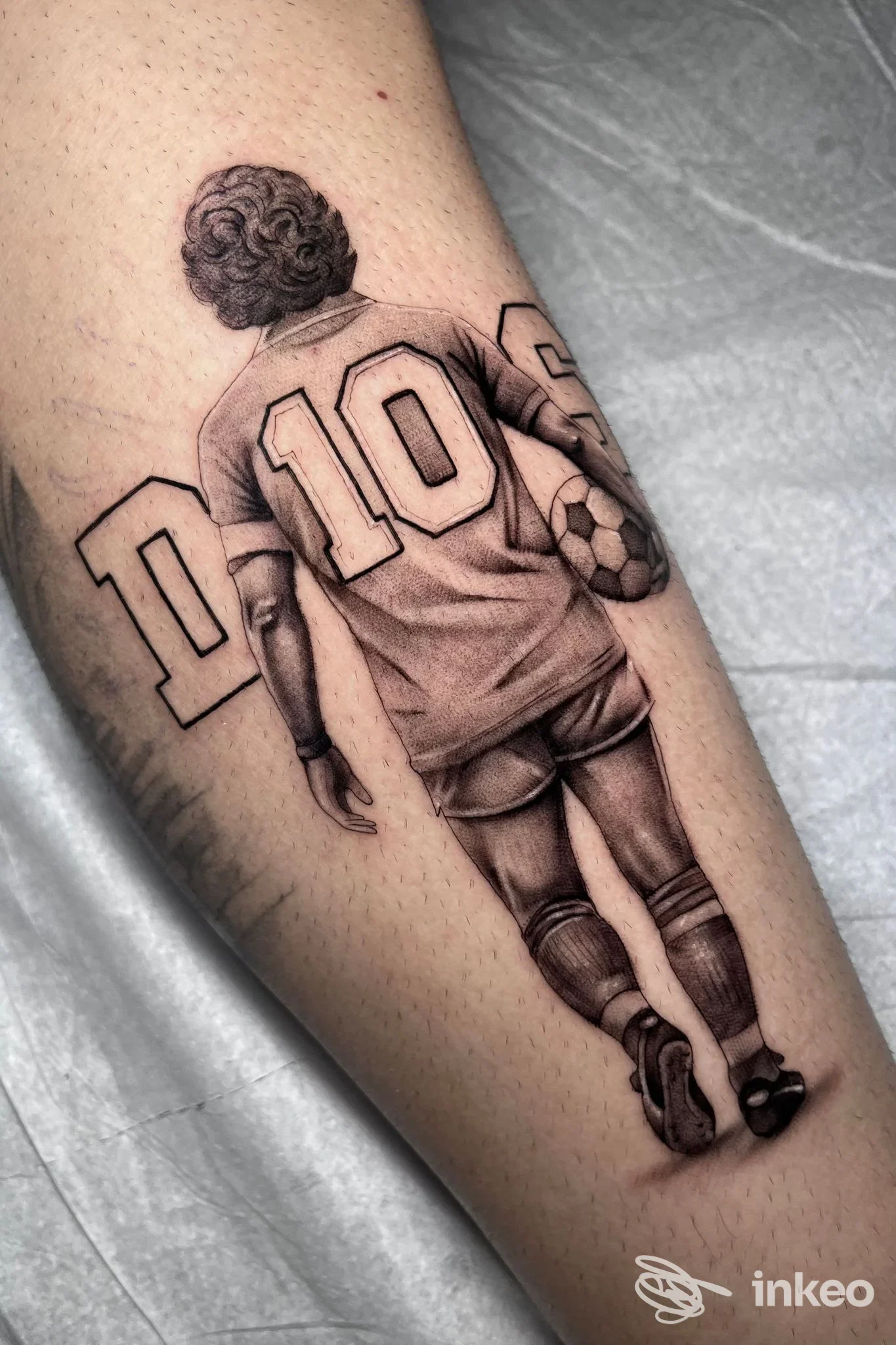 Tatuaggio realistico in bianco e nero di un calciatore visto di spalle sul polpaccio, Bronx Tattoo, Riva del Garda.