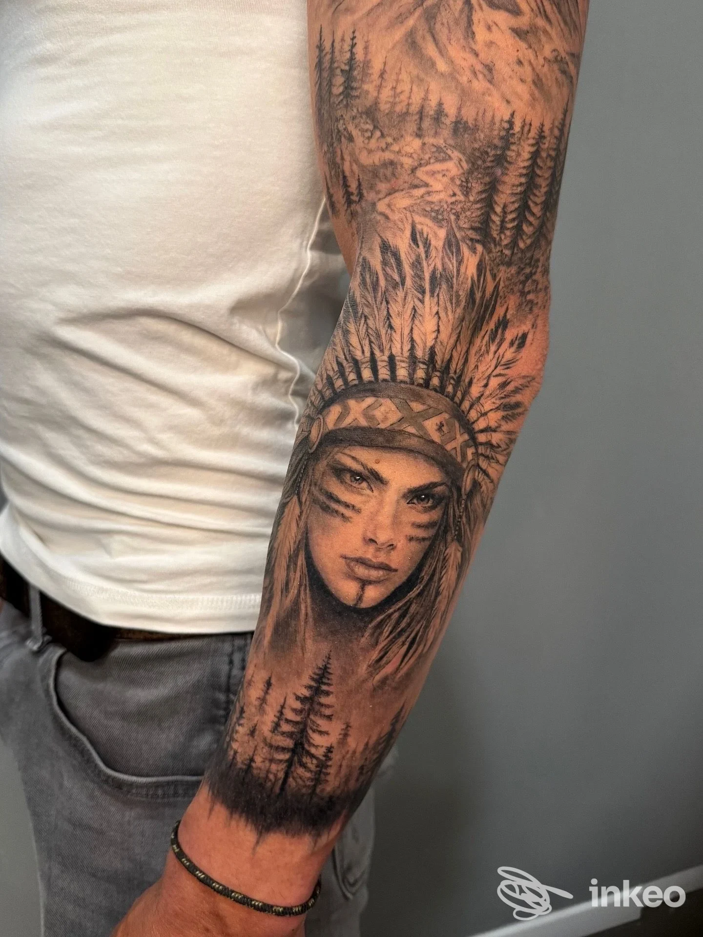 Manica tatuata sul braccio con volto femminile e paesaggio di alberi, immagine fornita da DEVI TATTOO, Levico Terme.