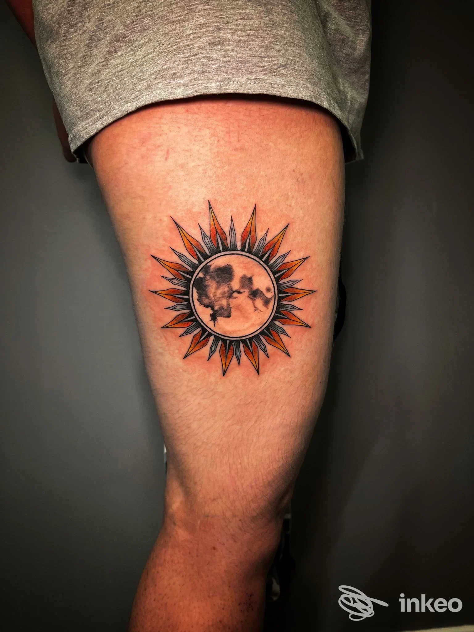 Tatuaggio a forma di sole con disco centrale sulla coscia, linee nere e sfumature arancioni — DEVI TATTOO, Levico Terme.