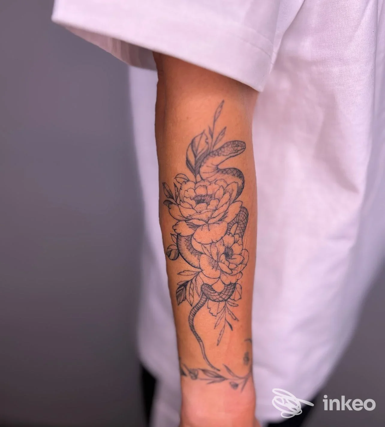 Tatuaggio floreale con serpente sull'avambraccio, fotografia di un lavoro realizzato da Elli Ink Tattoo a Bressanone.