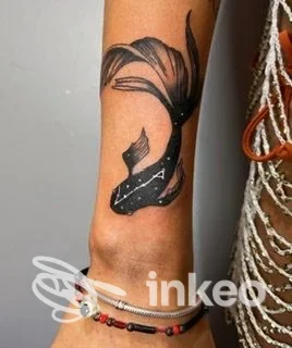 Primo piano di un tatuaggio a pesce koi nero sull'avambraccio vicino al polso, con braccialetti; foto inviata da EDL TATTOO, Corvara in Badia.