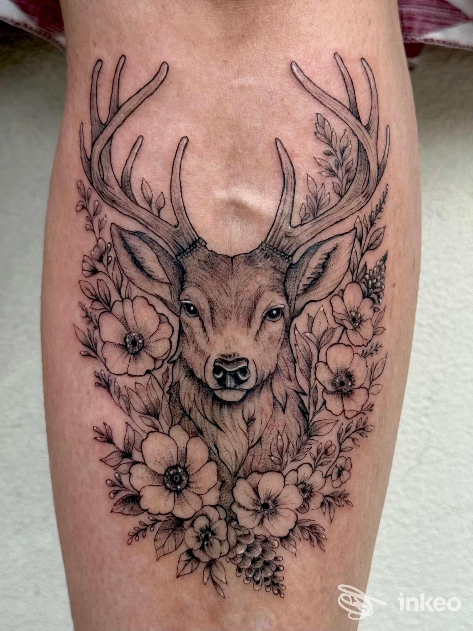 Tatuaggio sul polpaccio con testa di cervo avvolta da fiori, EDL TATTOO, Corvara in Badia.
