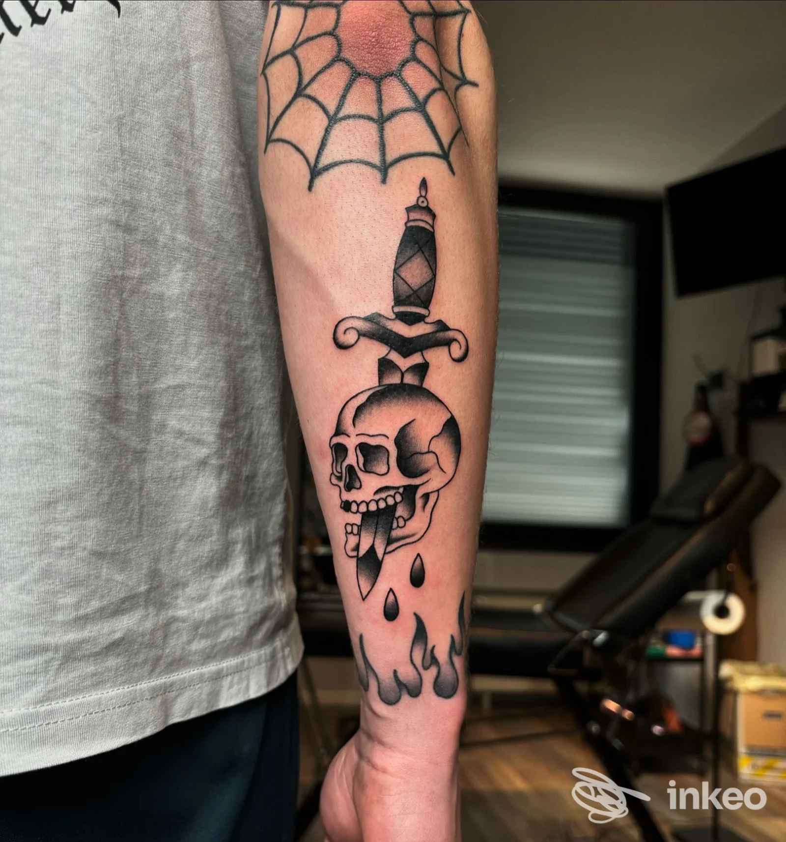Avambraccio tatuato con pugnale che attraversa un teschio e ragnatela, foto realizzata presso Inkmate Tattoo Studio, Levico Terme.