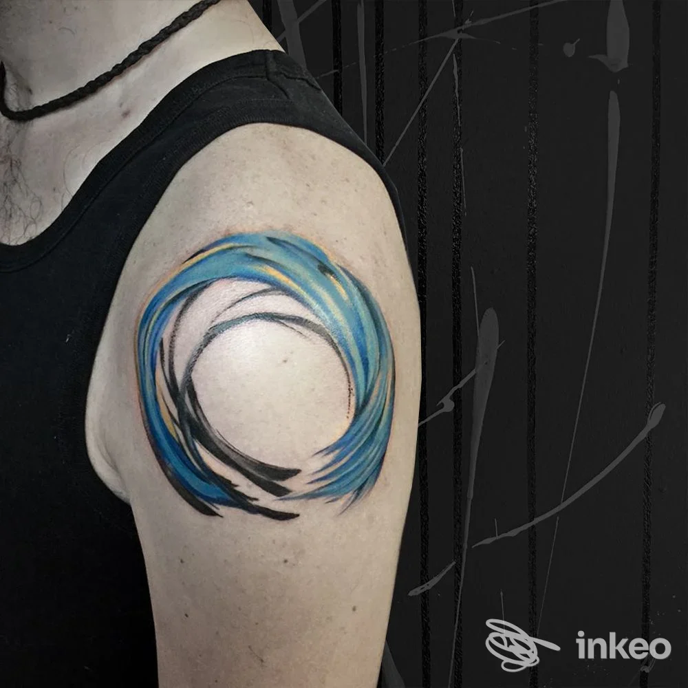Tatuaggio circolare astratto con pennellate blu sul deltoide, Hirsch Concept Store a Pinzolo.