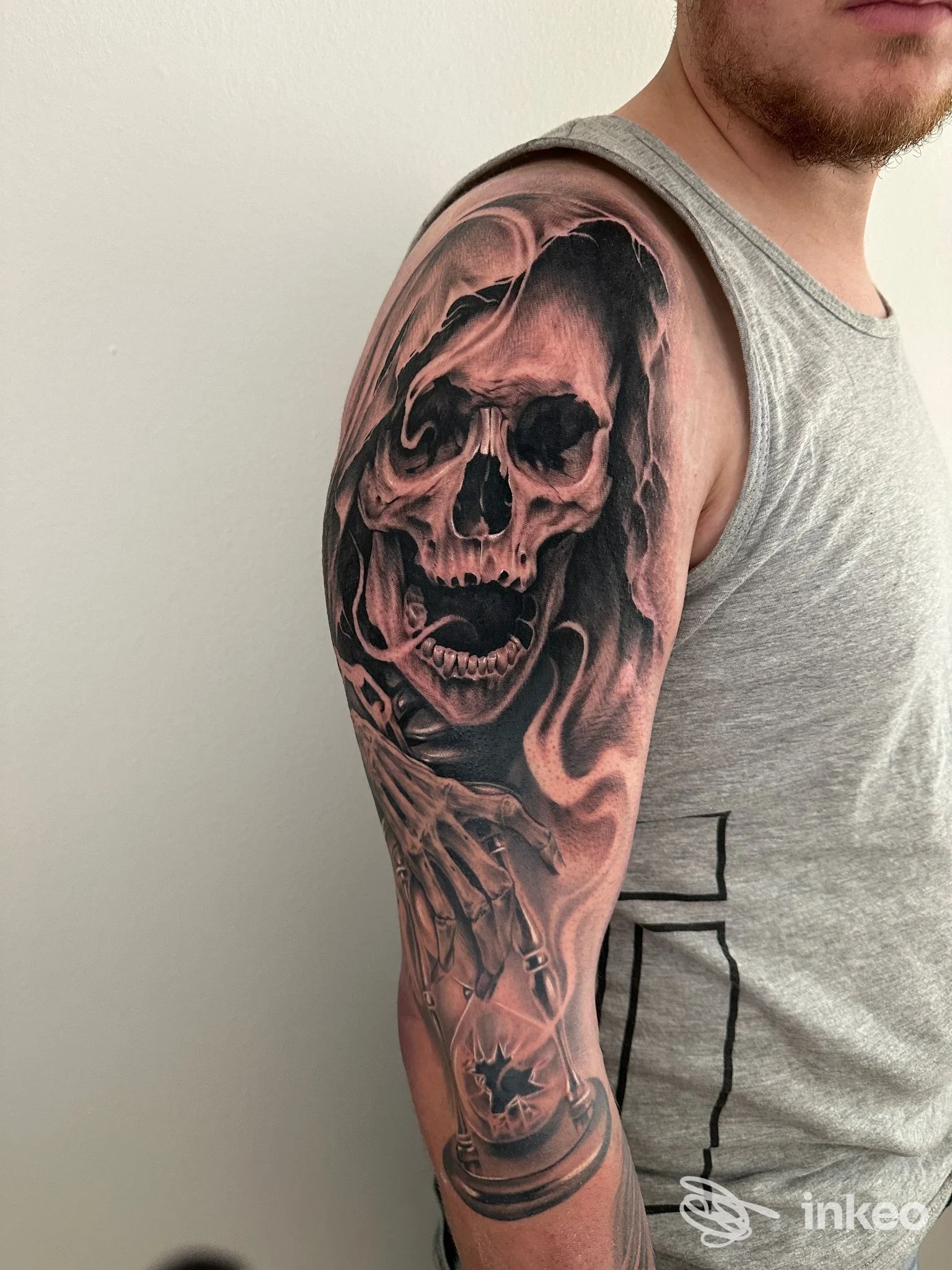 Mezza manica con teschio realistico e clessidra sul braccio di un uomo, lavoro fotografato presso Infamous Tattoo a Campo Tures.