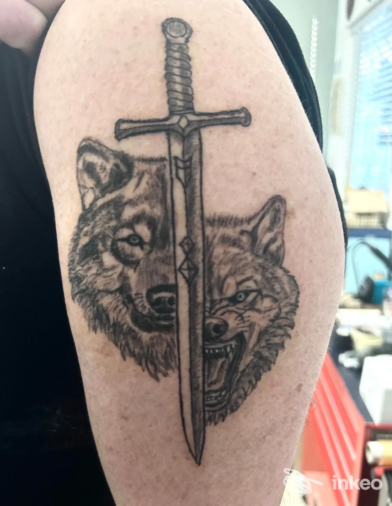 Tatuaggio black & grey con due teste di lupo e una spada sul braccio superiore — Jack Art - Tattoo & Piercing, Laives.