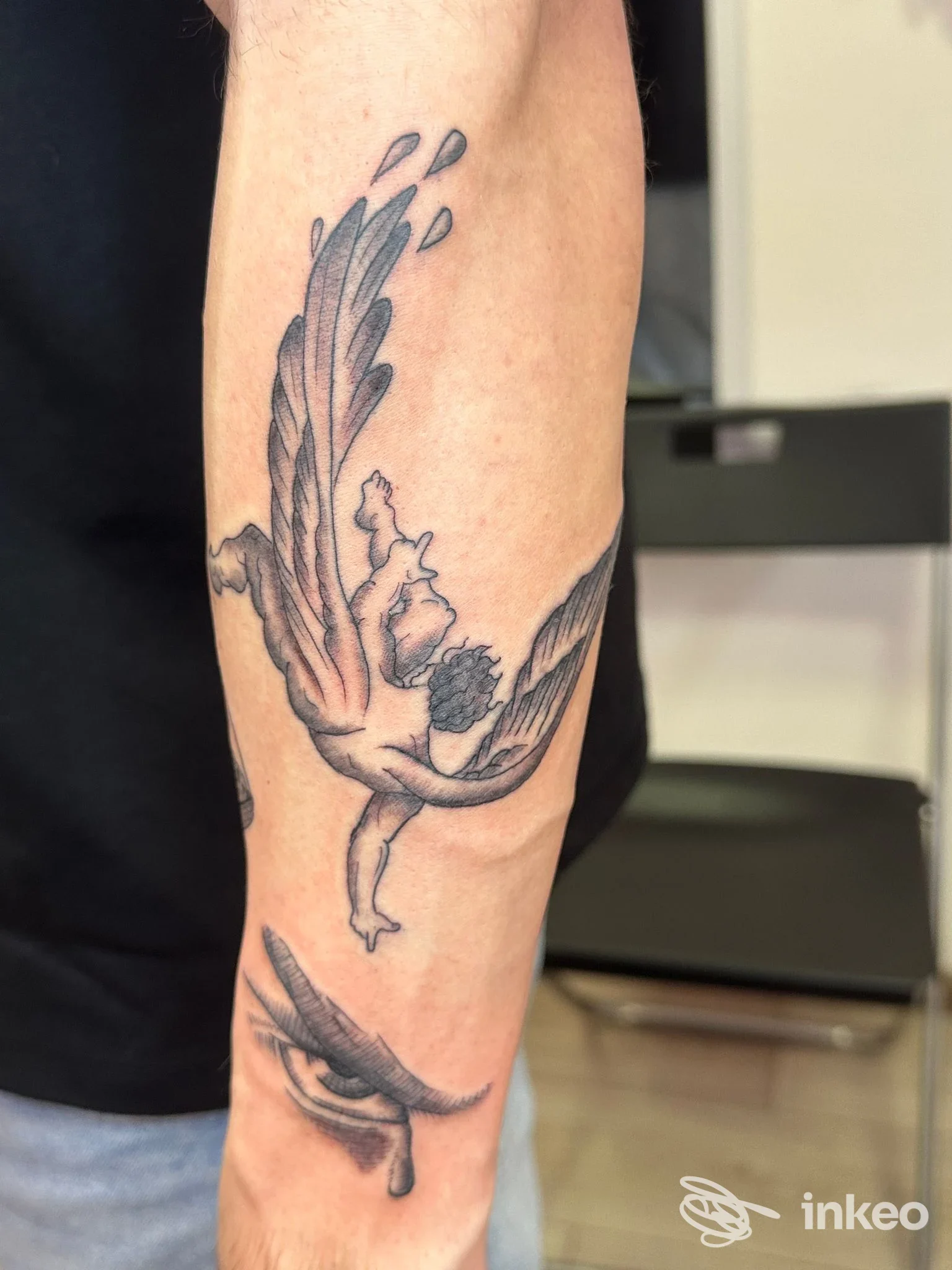 Tatuaggi black & grey su avambraccio: un angelo alato e un occhio stilizzato. Foto dallo studio La Ceres Tattoo, Levico Terme.