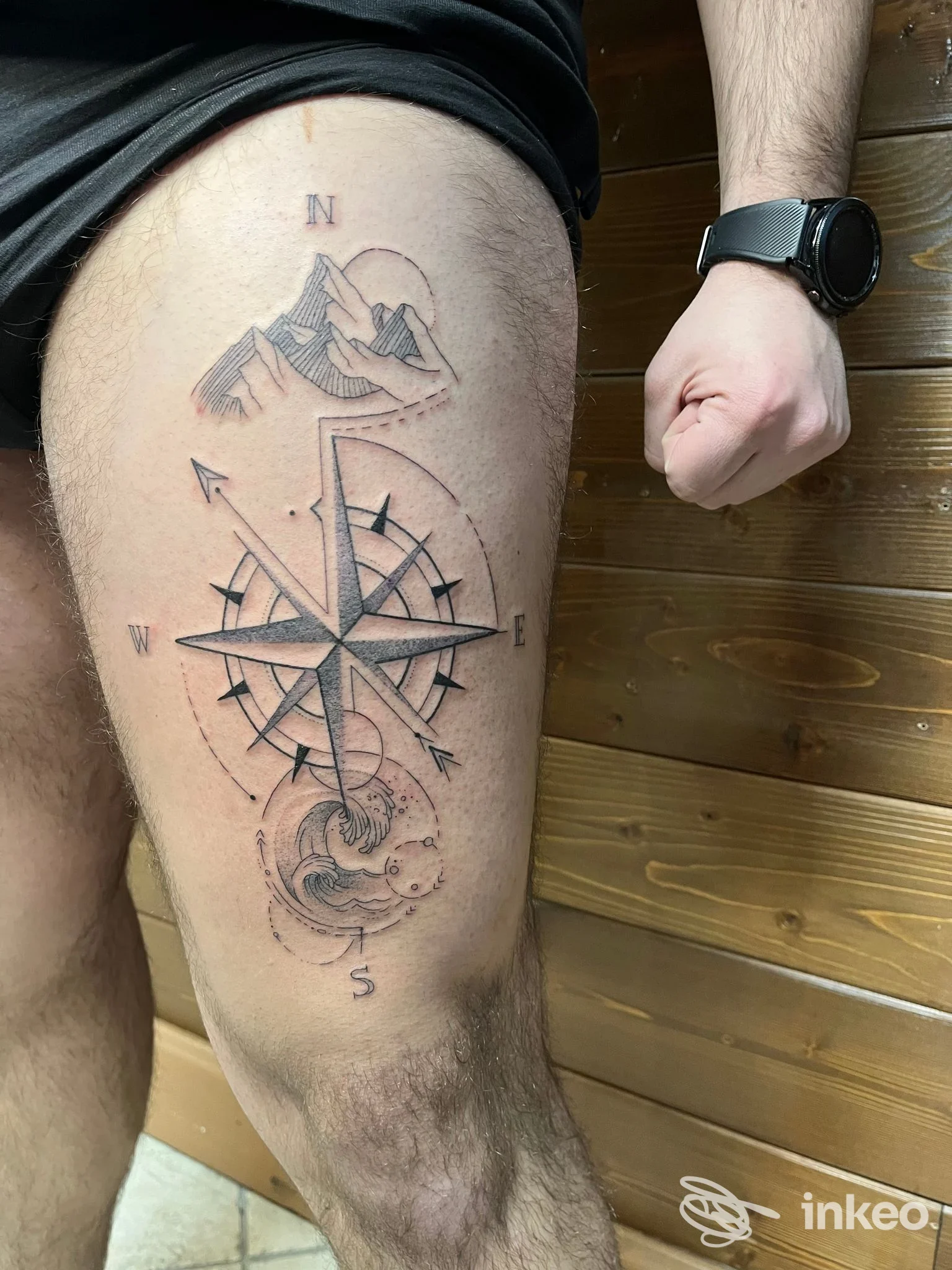 Tatuaggio a rosa dei venti con montagne e onda sulla coscia presso La Maggie Tattoo Studio, Primiero San Martino di Castrozza.