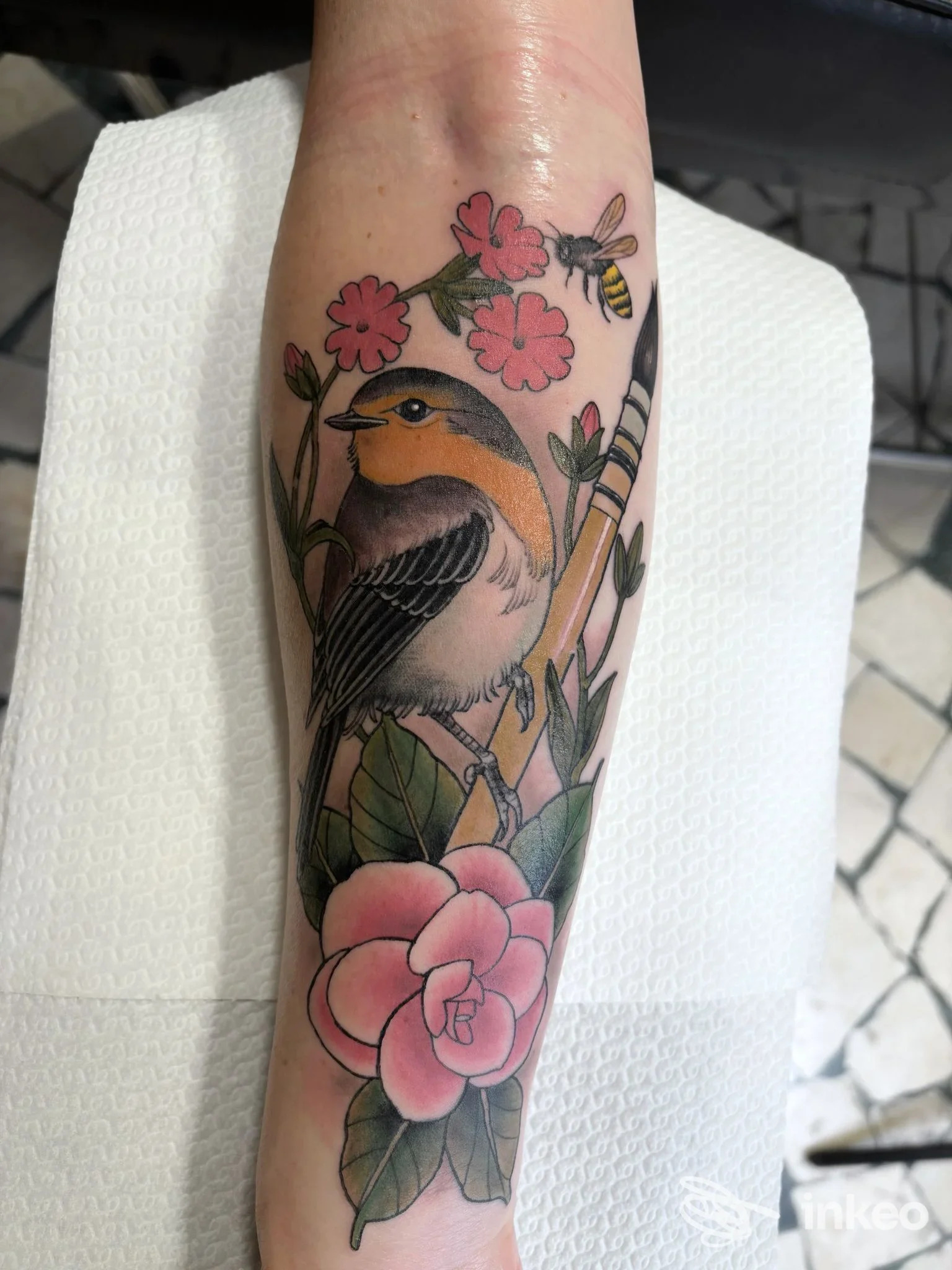 Tatuaggio a colori sull'avambraccio con uccello, fiori e ape, foto da La Montanara Tatuata, Borgo Valsugana.