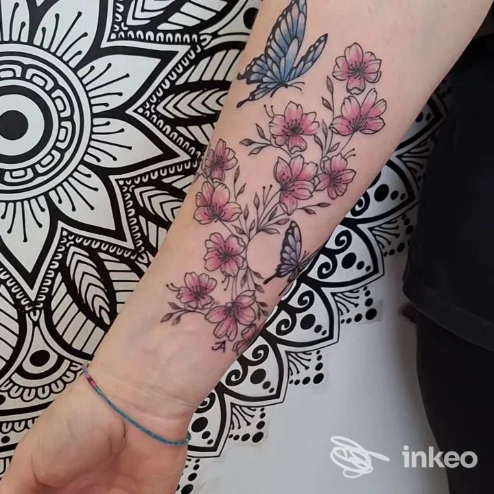 Tatuaggio floreale con farfalle su avambraccio, fotografia dallo studio Mad Queen Tattoo a Bolzano.
