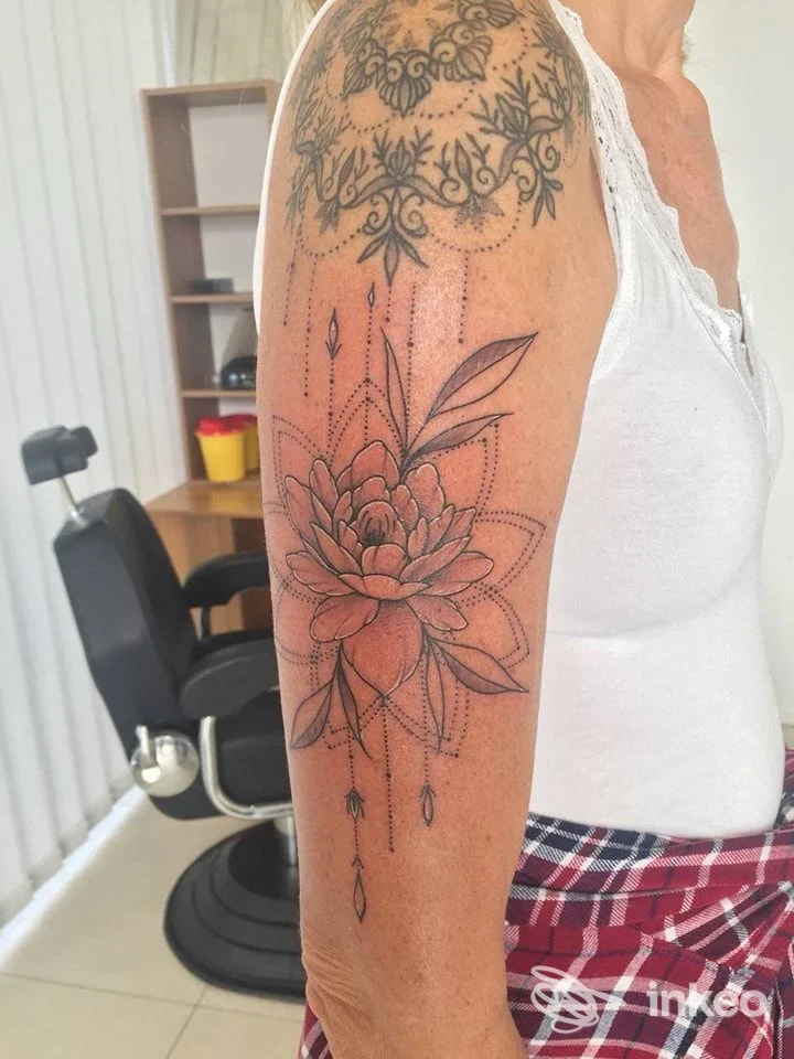 Tatuaggio floreale geometrico a inchiostro nero sul braccio superiore, foto dallo studio MozArt Tattoo & Piercing a Merano.
