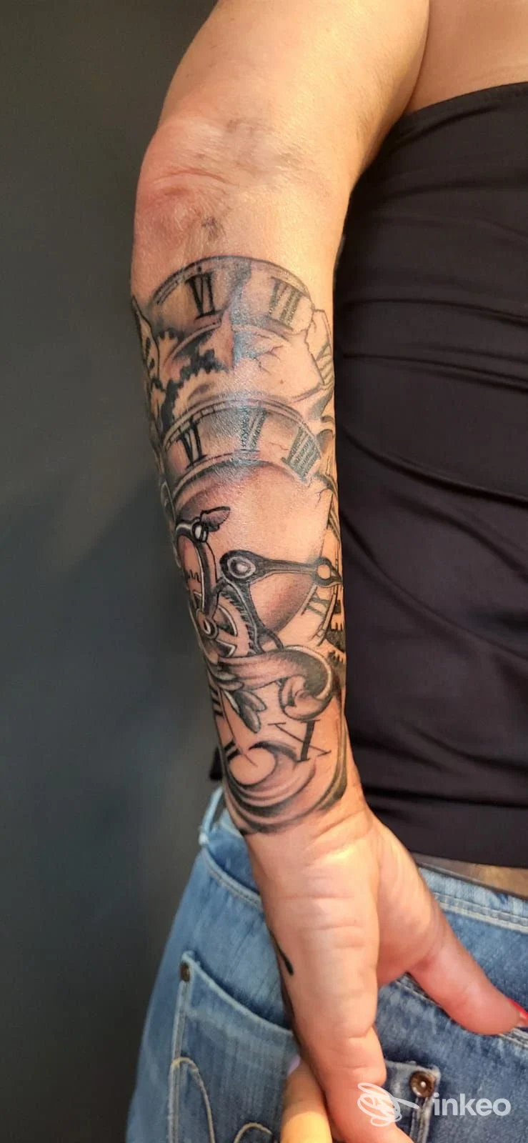 Tatuaggio in bianco e nero con elementi meccanici e lancette d'orologio sull'avambraccio, foto fornita da Naked Tattoo, Sarentino.