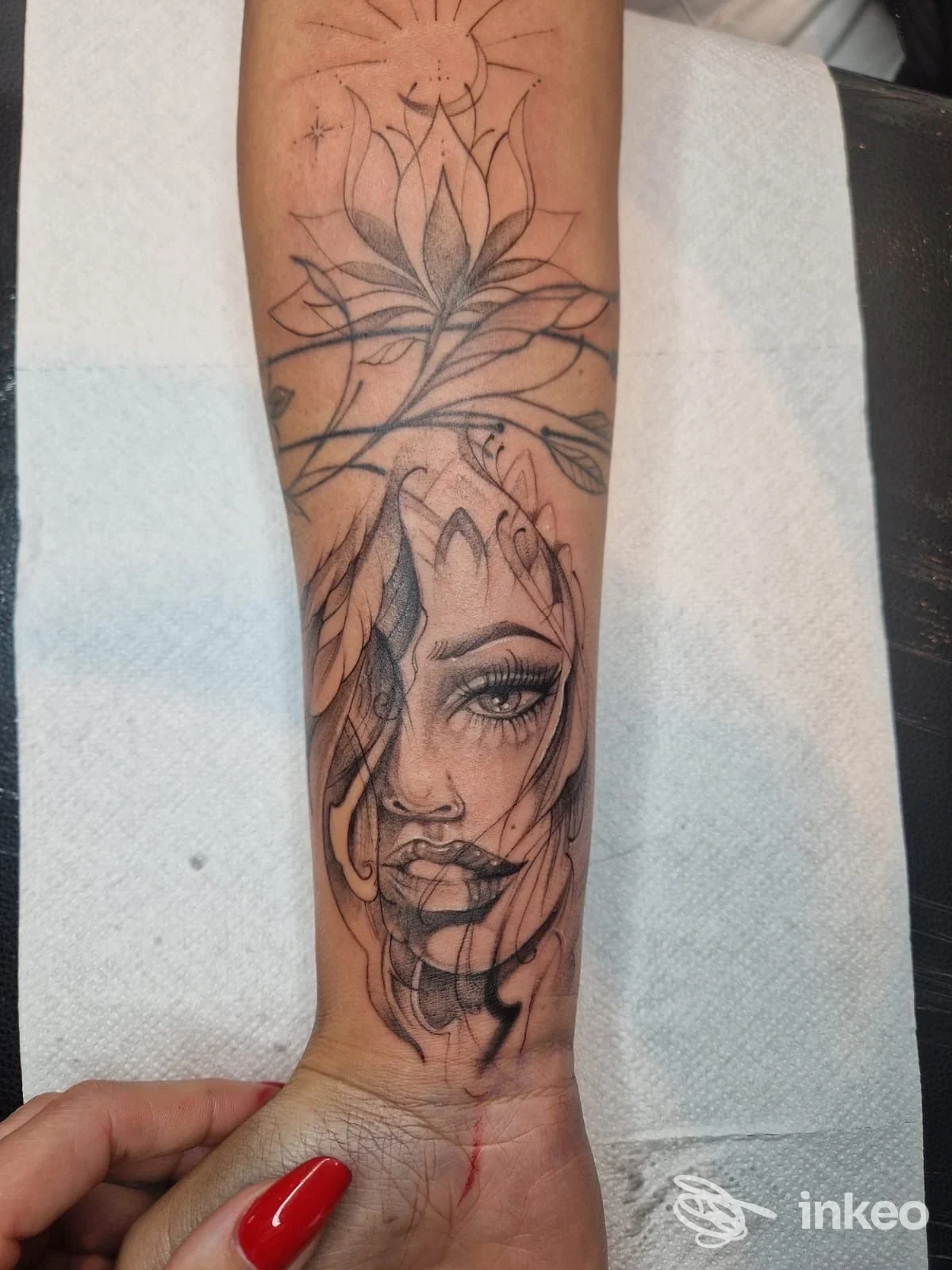 Tatuaggio in nero e grigio sul polso/avambraccio con volto femminile e motivi floreali, foto fornita da Naked Tattoo, Sarentino.