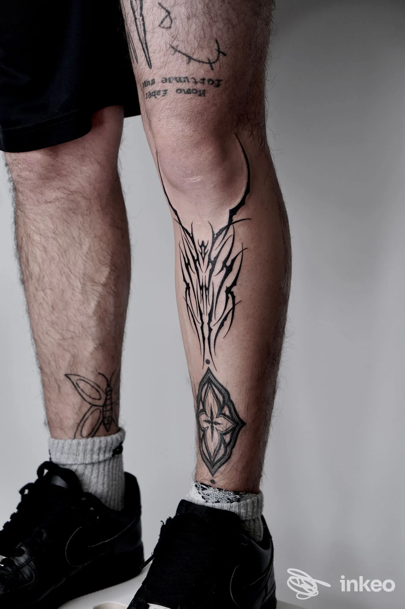 Tatuaggi neri ornamentali su ginocchio e polpaccio destro, fotografati per No Name Tattoo Studio, Trento.