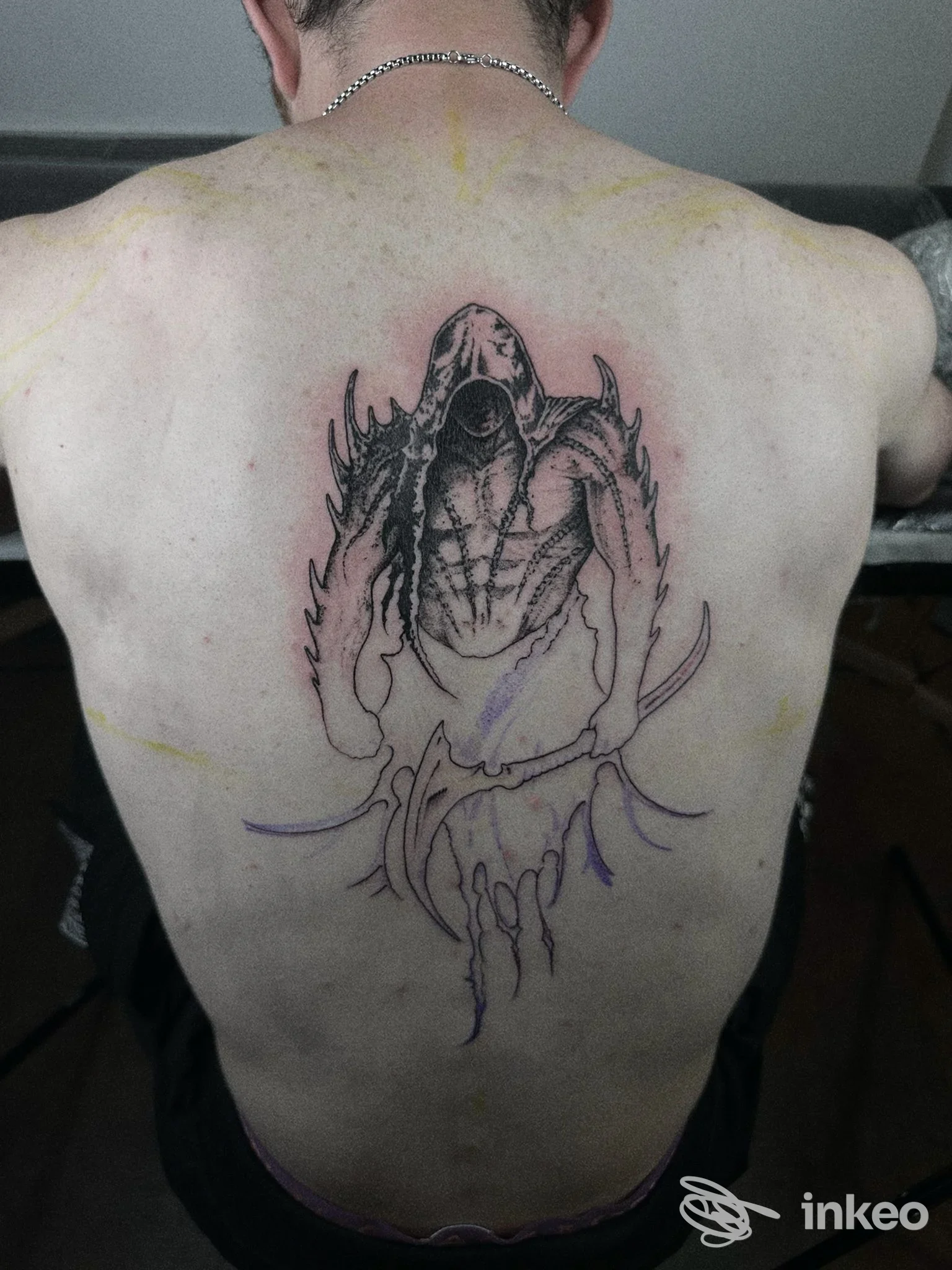 Tatuaggio nero centrale in lavorazione sulla schiena di un cliente, No Name Tattoo Studio, Trento.