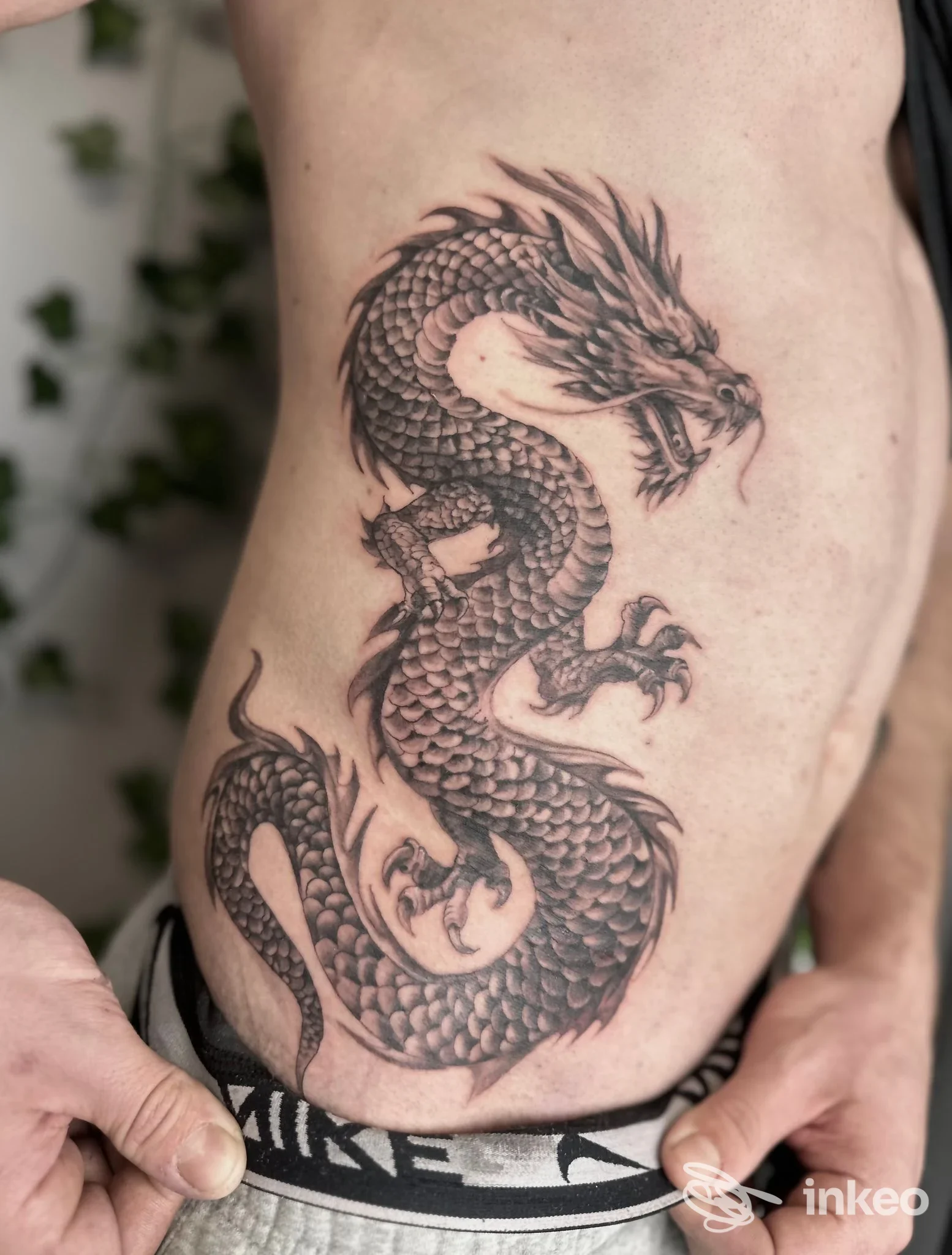 Grande tatuaggio in bianco e nero di un drago sul fianco destro di una persona, realizzato da Queens Tattoo a Brunico.