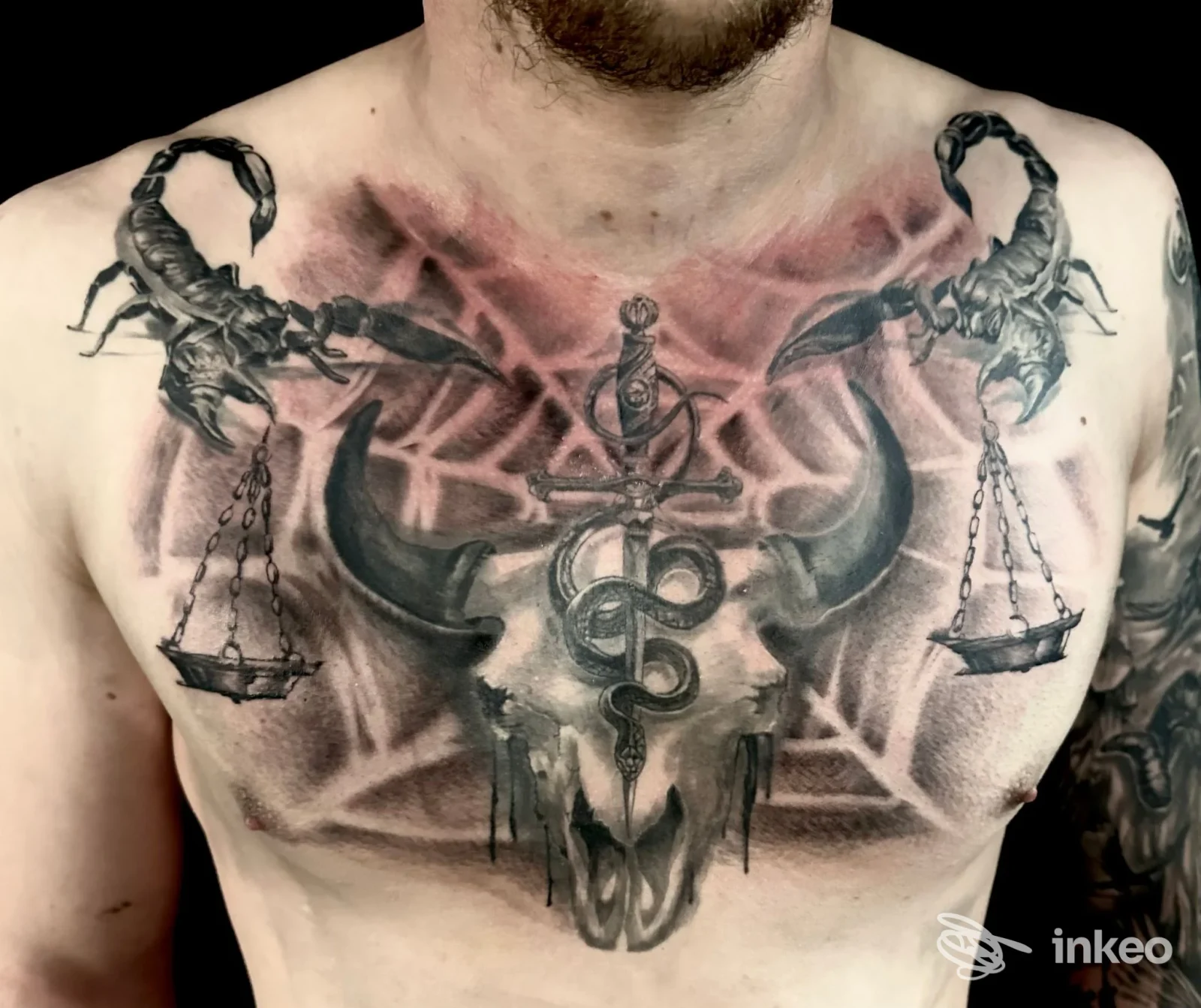 Ampio tatuaggio su petto con teschio, serpente e bilance, realizzato da Queens Tattoo a Brunico.