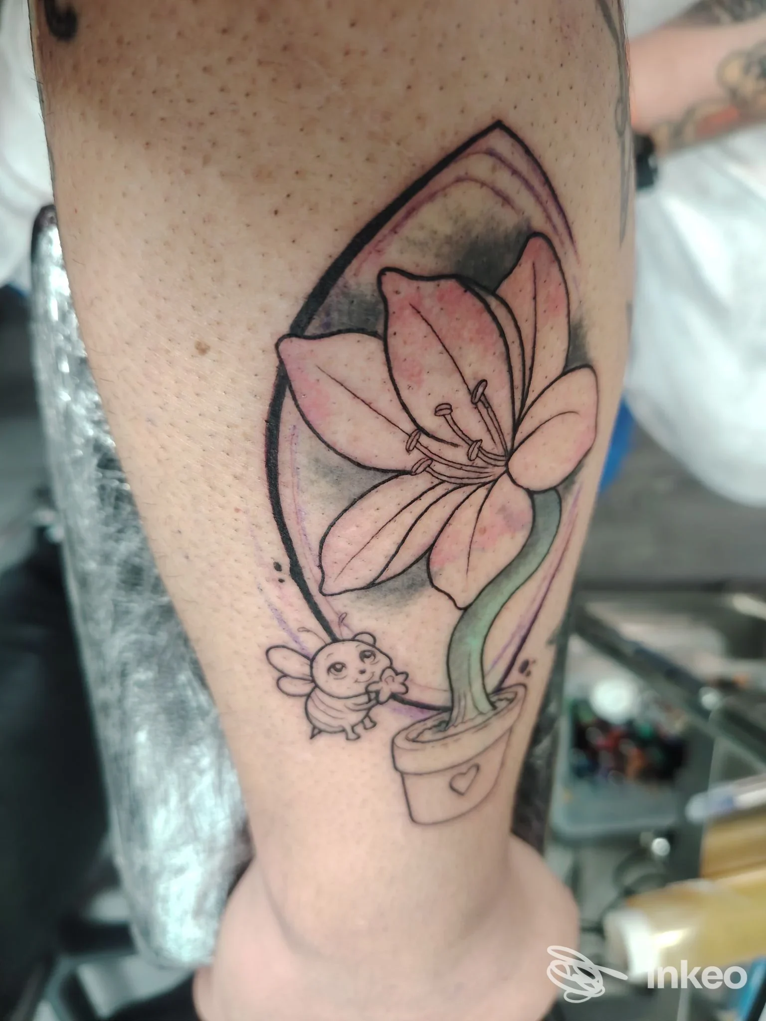 Tattoo su pelle raffigurante un grande giglio rosa in vaso, con contorni neri e sfumature, visibile su gamba; a lato una piccola figura animale, in stile linework colorato, nello studio Black Rose Tattoo a Brescia.