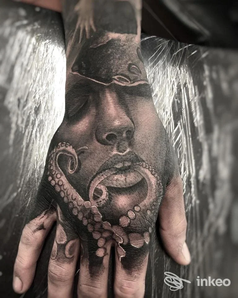 Tatuaggio in bianco e nero su dorso della mano con volto realistico e tentacoli, lavoro di SKY TATTOO BRUNECK a Brunico.