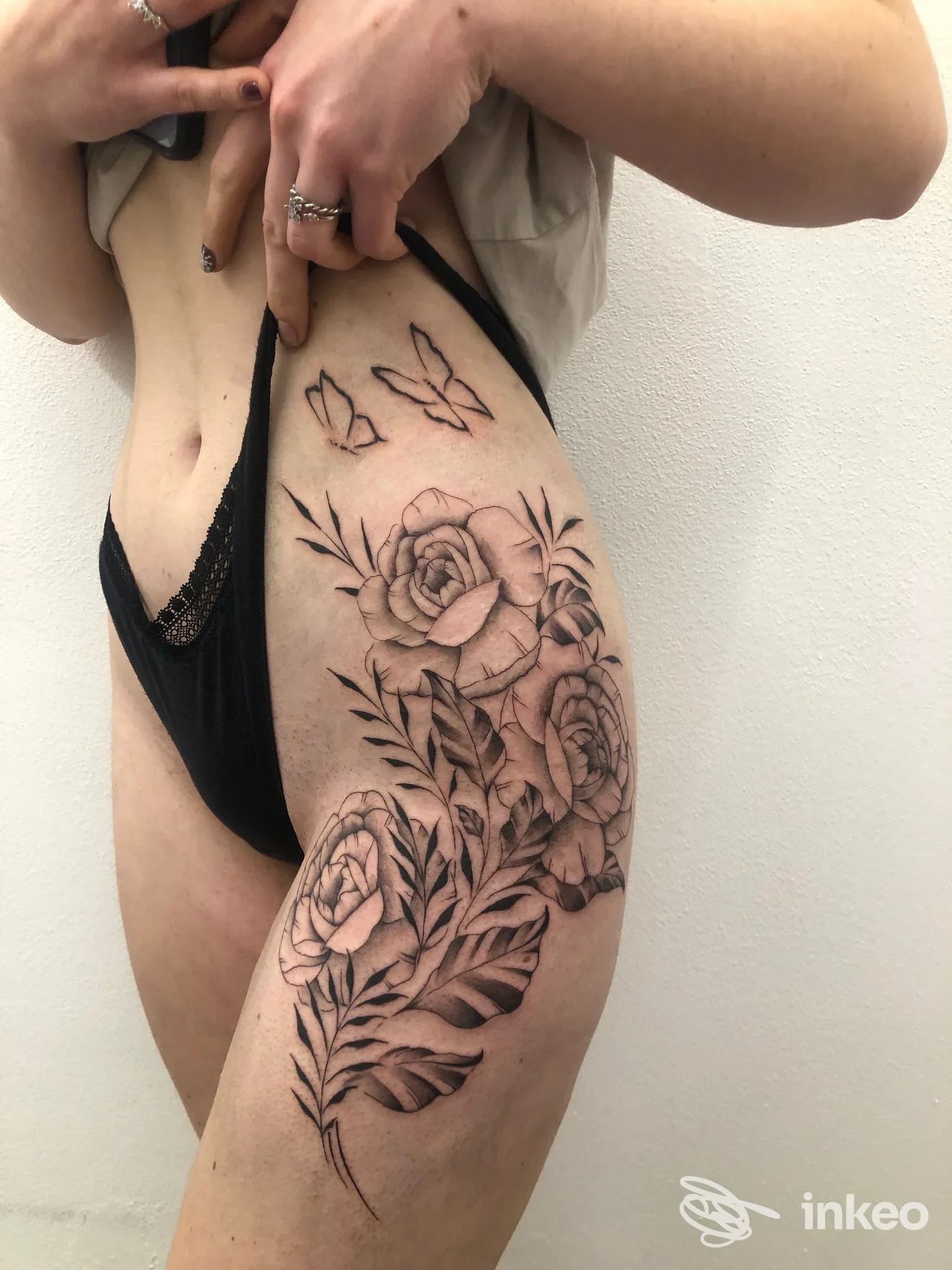 Tatuaggio floreale nero e grigio sul fianco e la coscia, Shakende Tattoo Studio, Fai della Paganella.