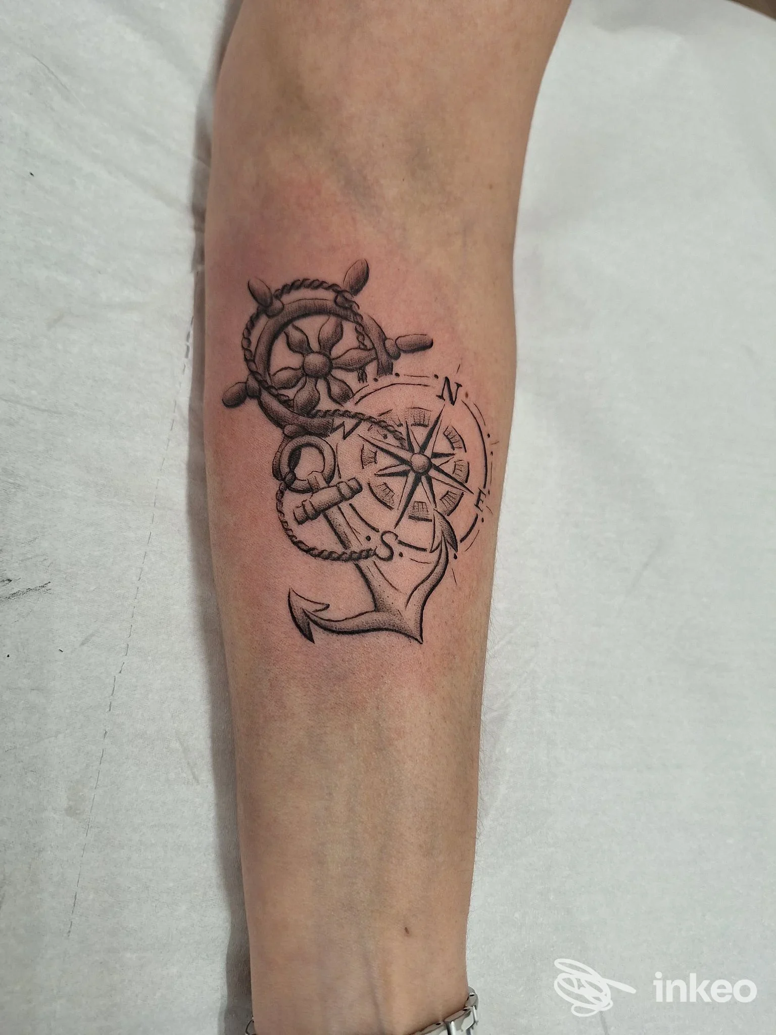 Tatuaggio su avambraccio con ancora, bussola e timone realizzato da Shakende Tattoo Studio a Fai della Paganella.