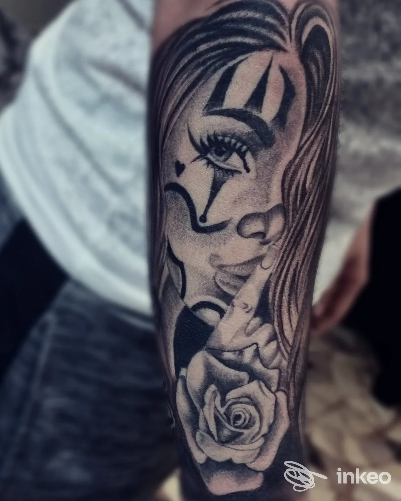 Tatuaggio in bianco e nero su avambraccio con volto da clown/maschera e una rosa, foto fornita da Skink Tattoo & Piercing, Bolzano.