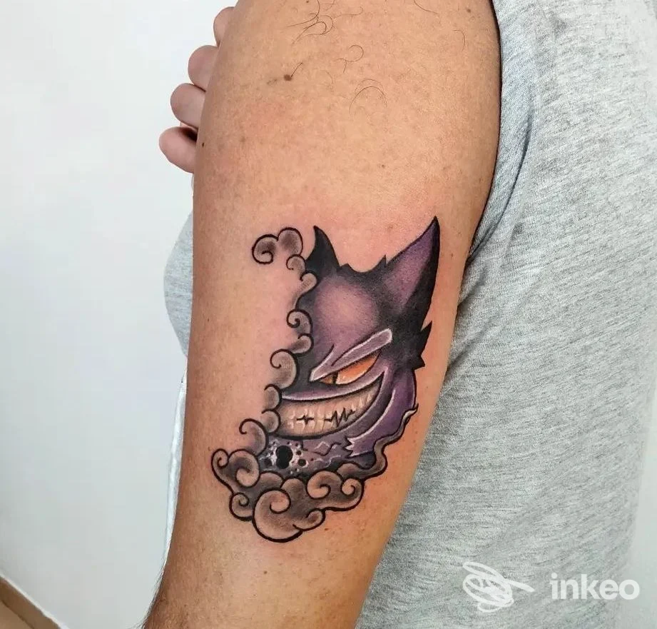 Tatuaggio colorato a forma di maschera su braccio superiore, foto fornita da Studio Croy Tattoo, Trento.